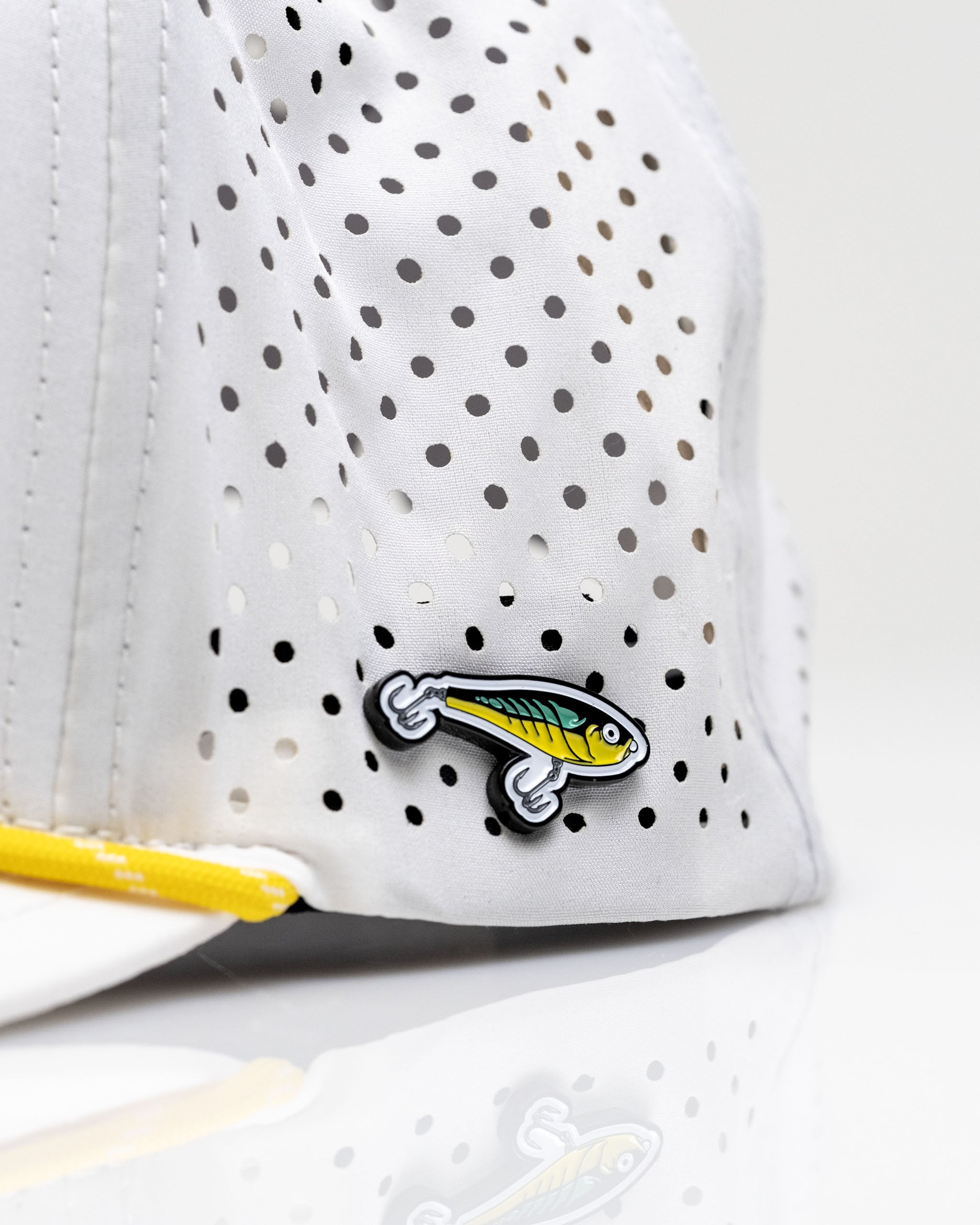 White perforated rope hat featuring a fishing lure design on the side, ideal for fishing enthusiasts.