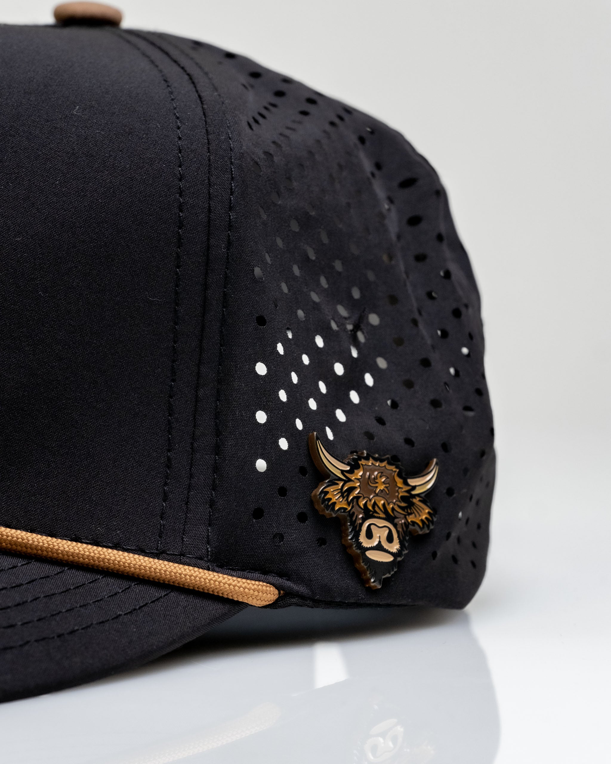 Highland Cow Collection Bundle features a stylish black golf cap with perforated design and a distinctive Highland cow emblem.