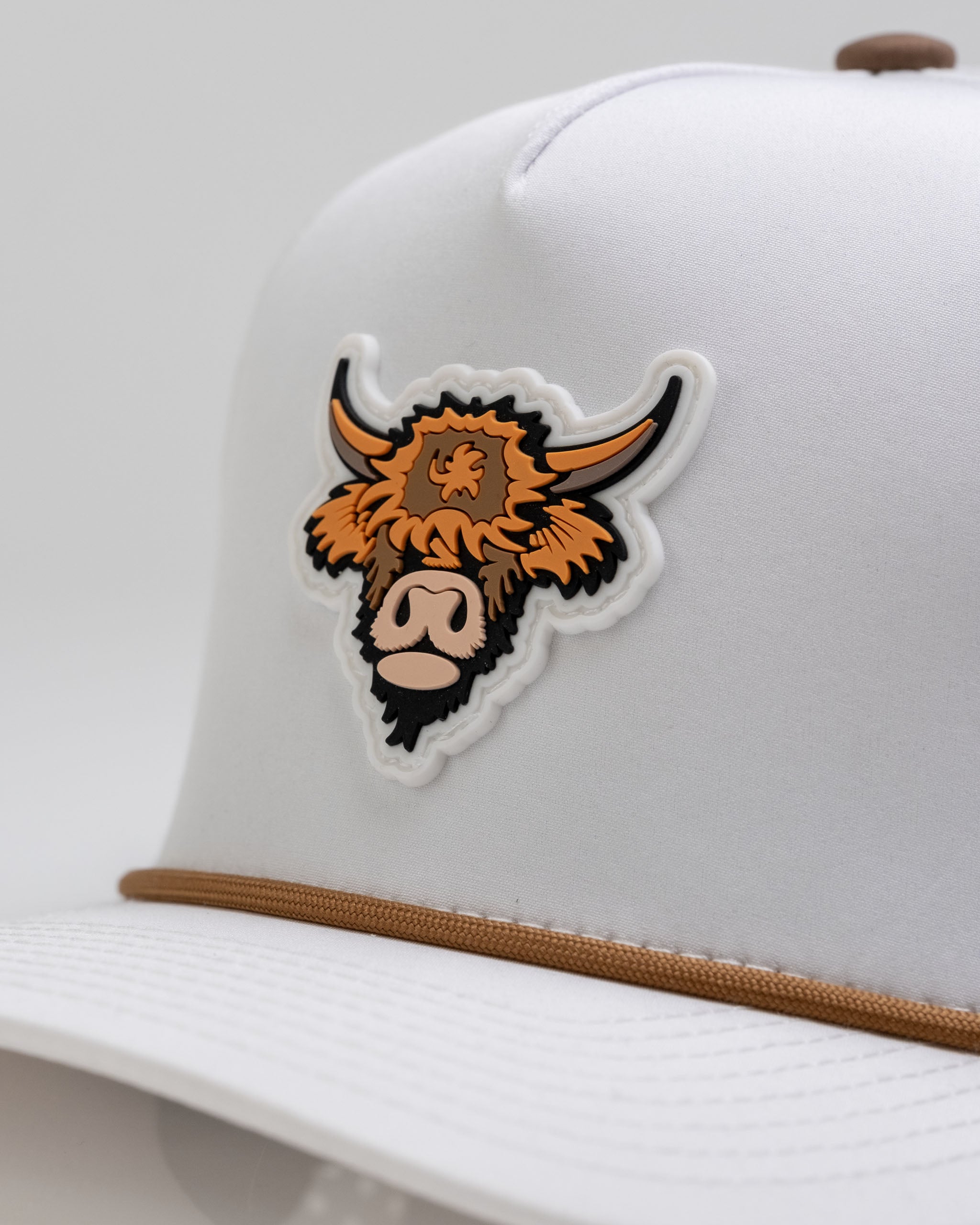Highland Cow White perforated rope hat featuring a bold cow graphic and a stylish brown rope accent.