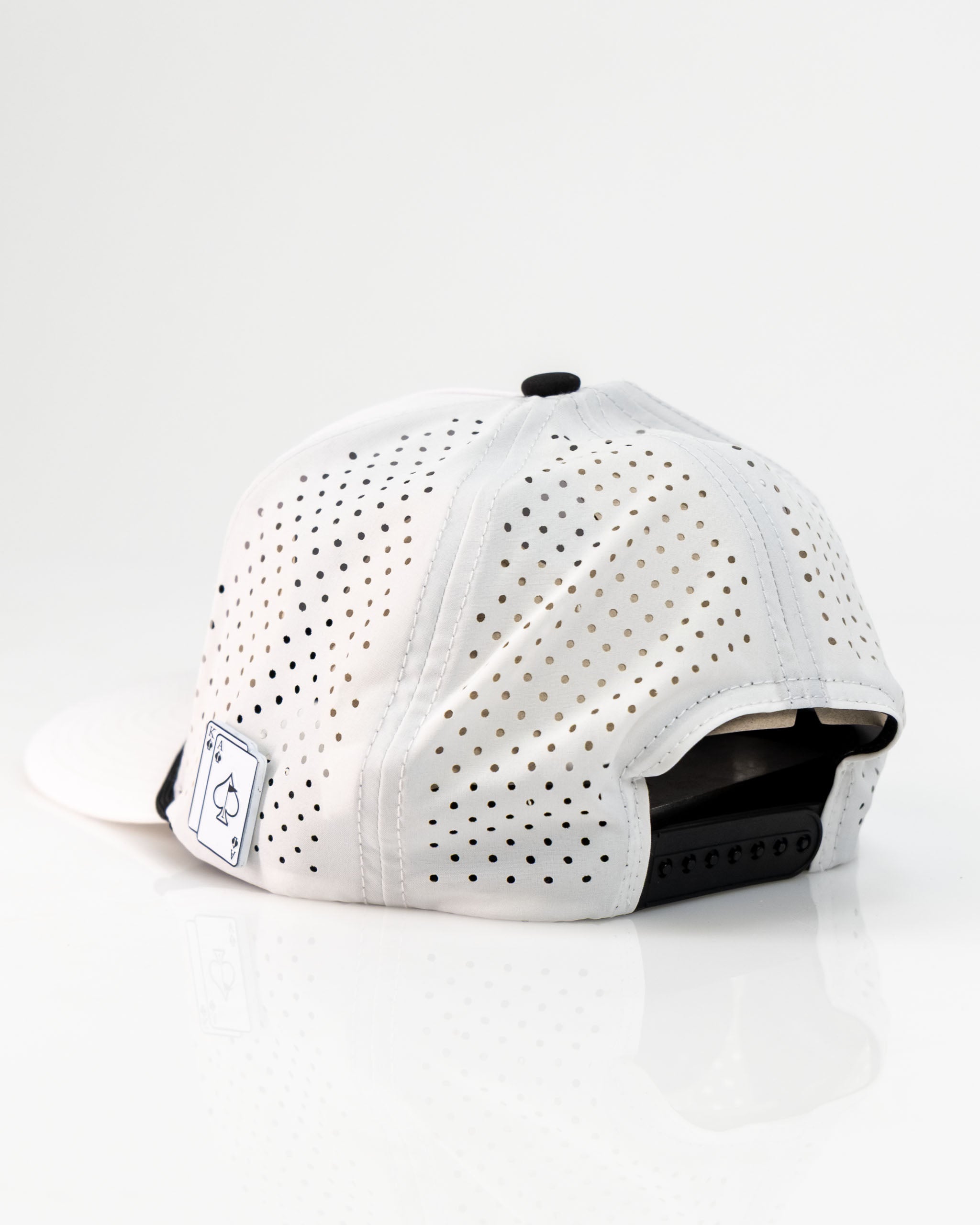 Perforated white rope hat with a black adjustable strap and logo patch on the back, designed for bold golfers.