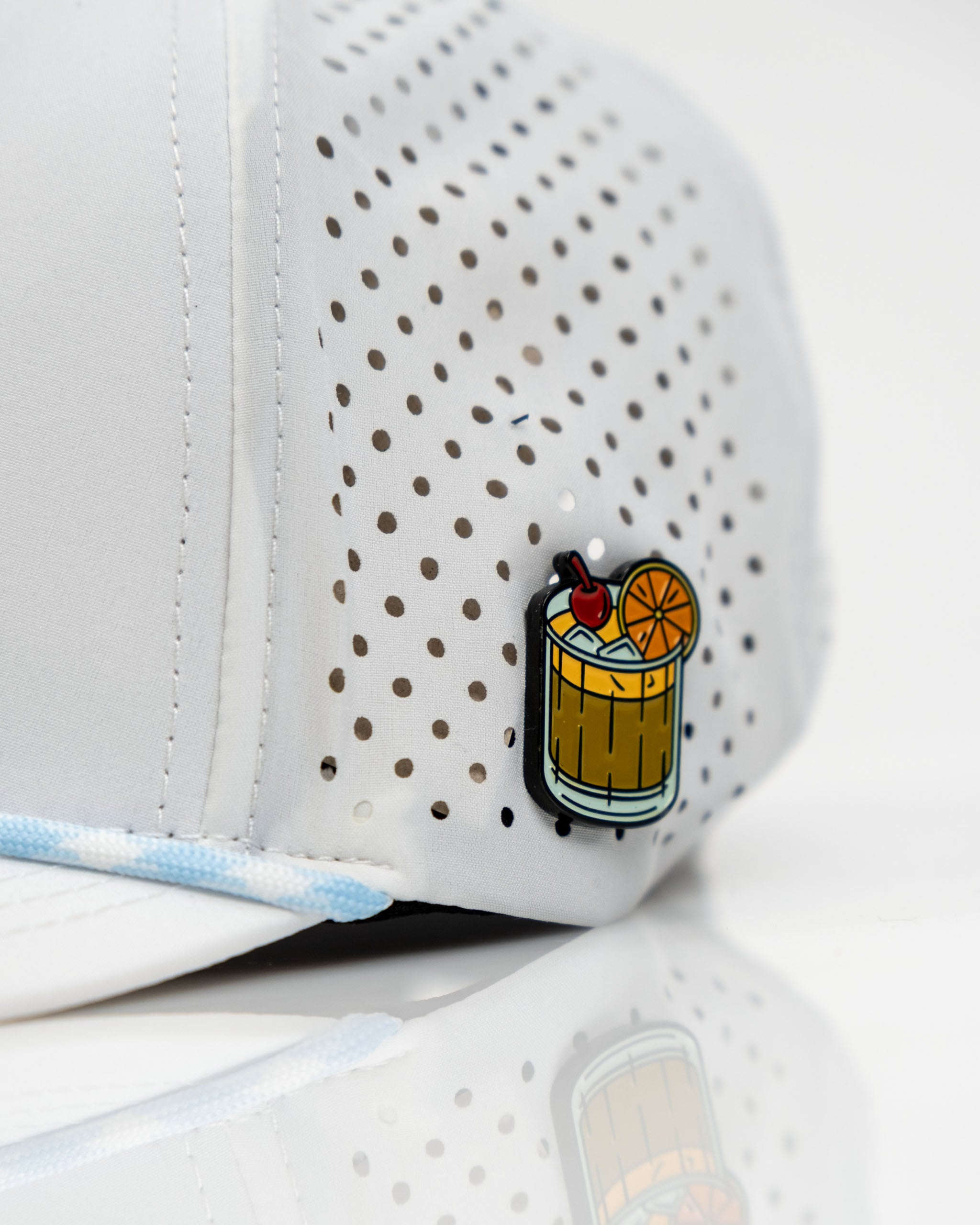 Perforated white rope hat featuring a colorful Old Fashioned cocktail graphic on the side, perfect for stylish golfers.