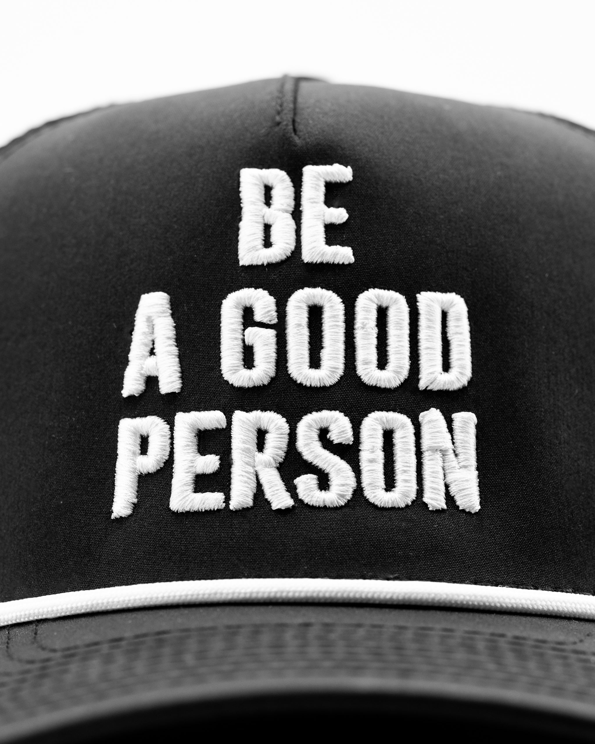 Black perforated rope hat featuring bold white embroidered text that reads "BE A GOOD PERSON.