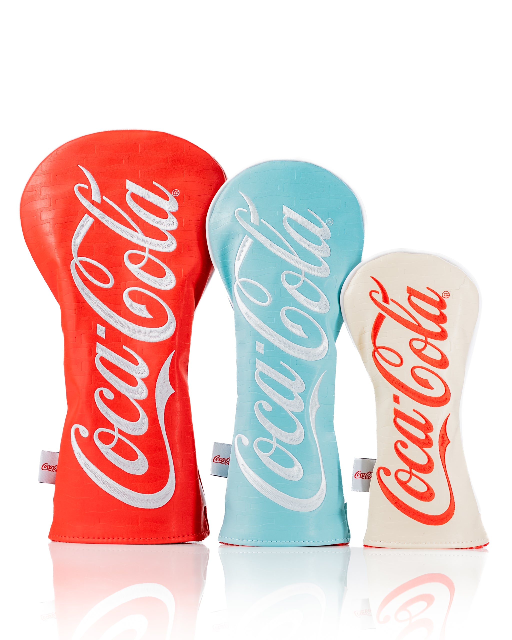 Coca-Cola headcover set featuring three vibrant covers in red, blue, and white with iconic logo designs for golf clubs.