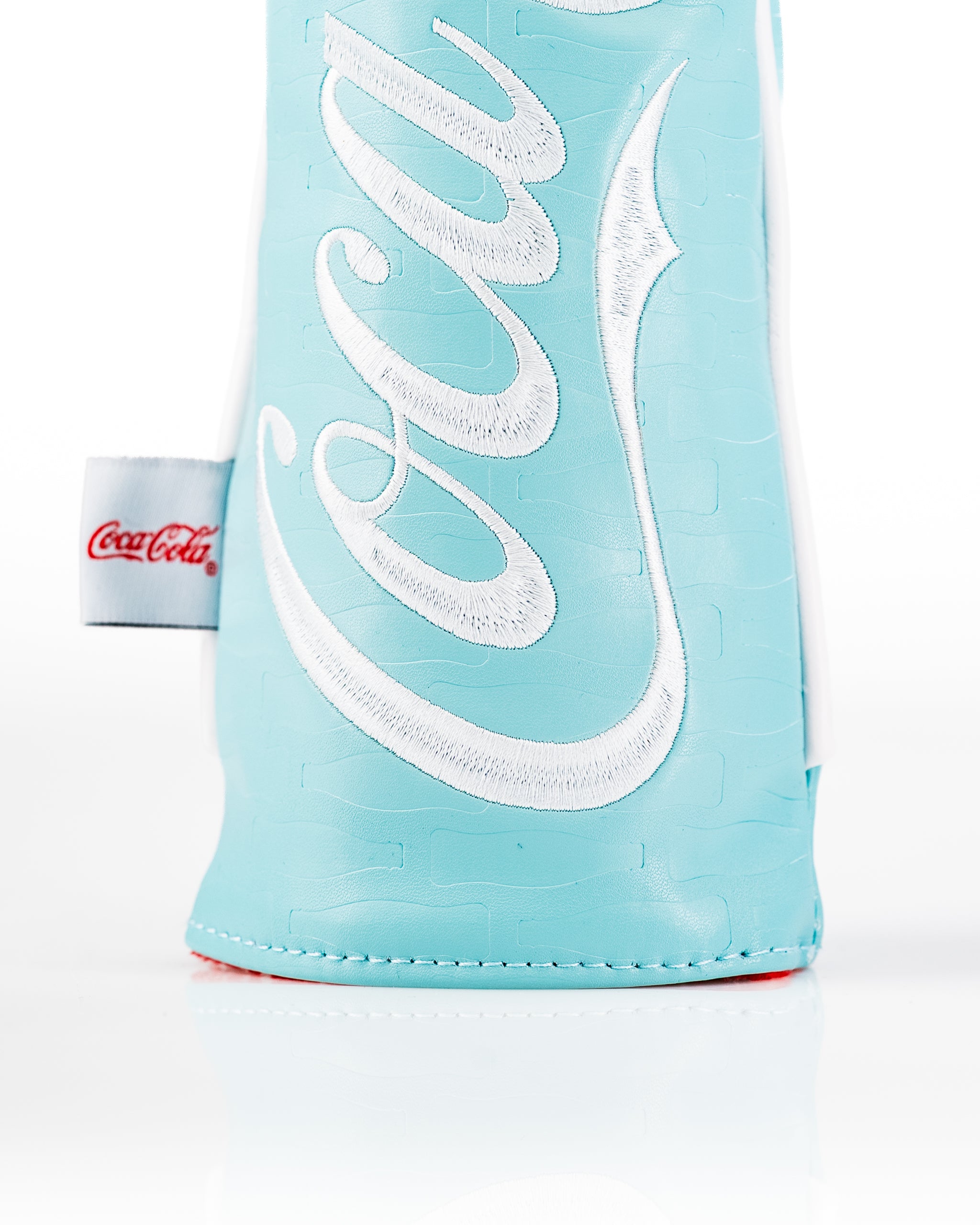 Coca-Cola fairway cover in light blue with embossed logo, designed for golfers seeking a stylish accessory.