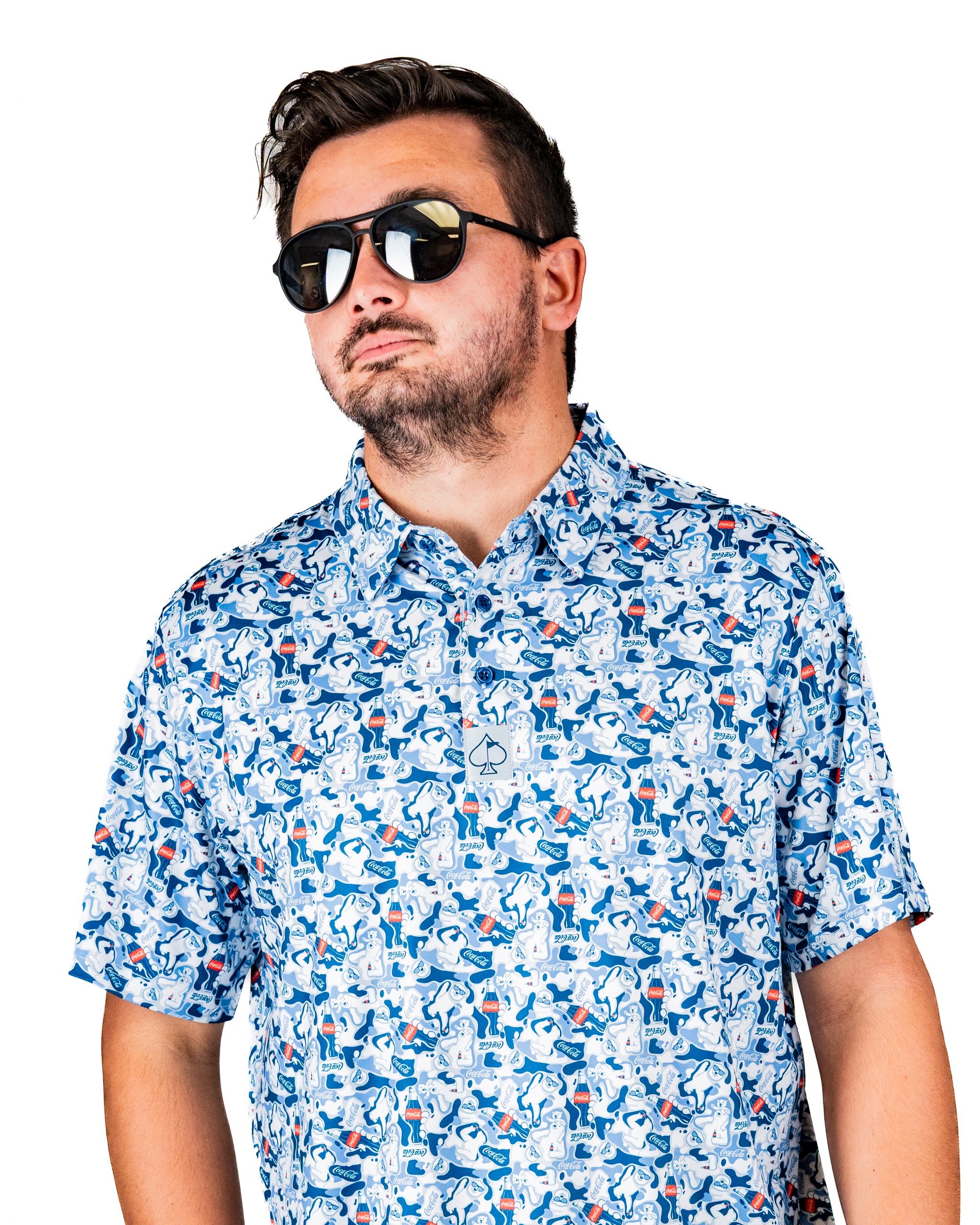 Man wearing a colorful short-sleeve shirt featuring a playful Coca-Cola pattern, paired with stylish sunglasses.