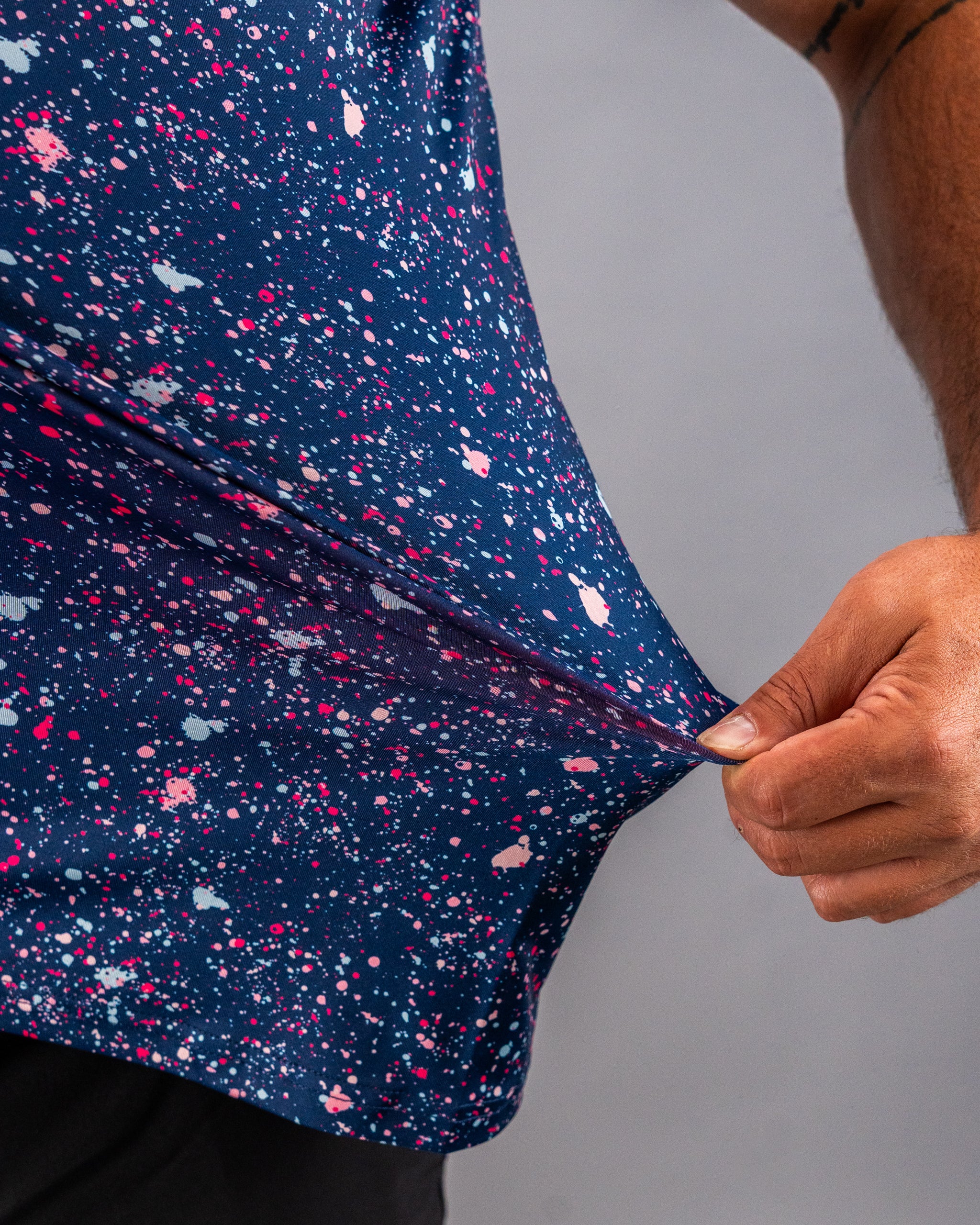 Bold blue splatter golf shirt featuring vibrant pink and white paint splashes, showcasing unique style and comfort.