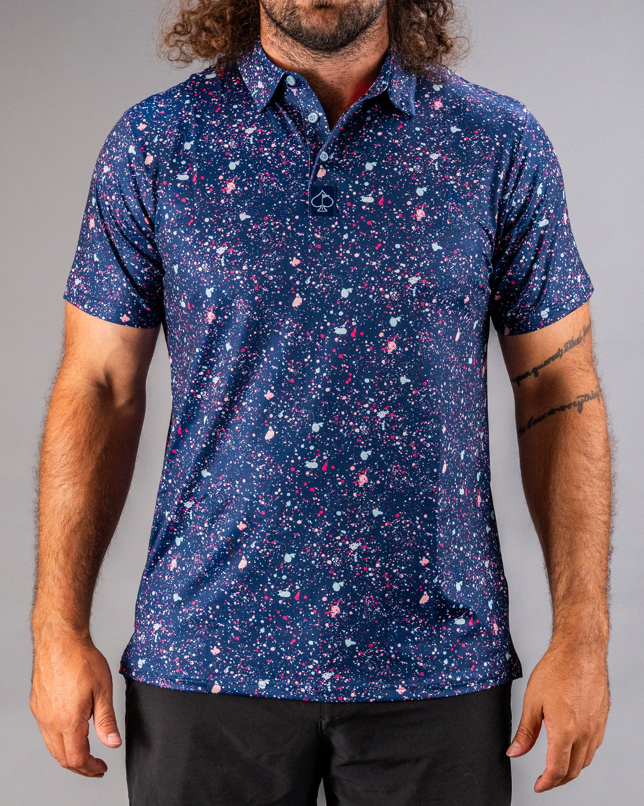 Men's blue golf polo featuring a vibrant splatter pattern in pink and white, perfect for making a bold statement on the course.