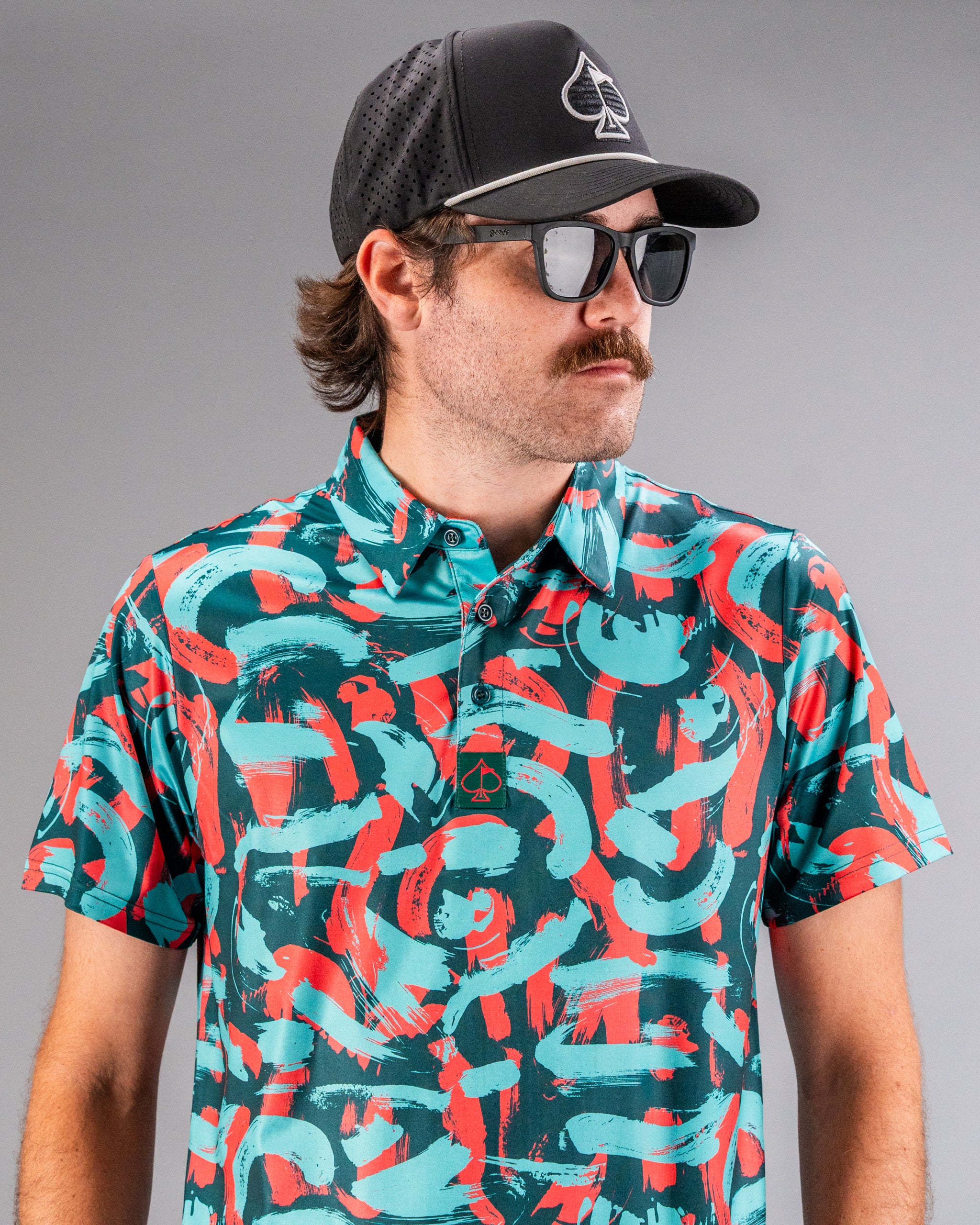 Bold golf polo featuring a vibrant coral and teal paint stroke pattern, perfect for standing out on the course.