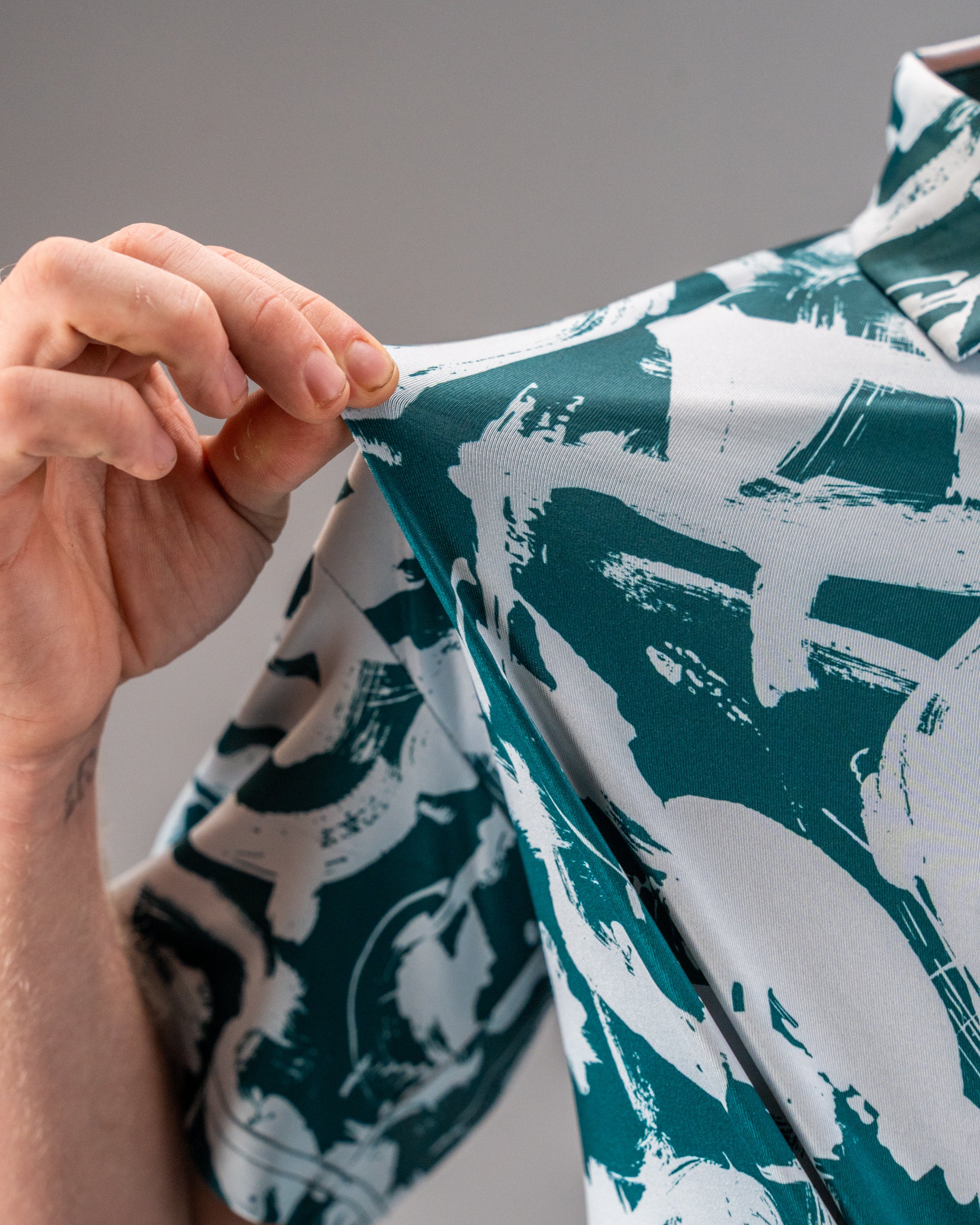 Bold green golf shirt featuring dynamic white paint stroke patterns, showcasing a close-up of the fabric texture.