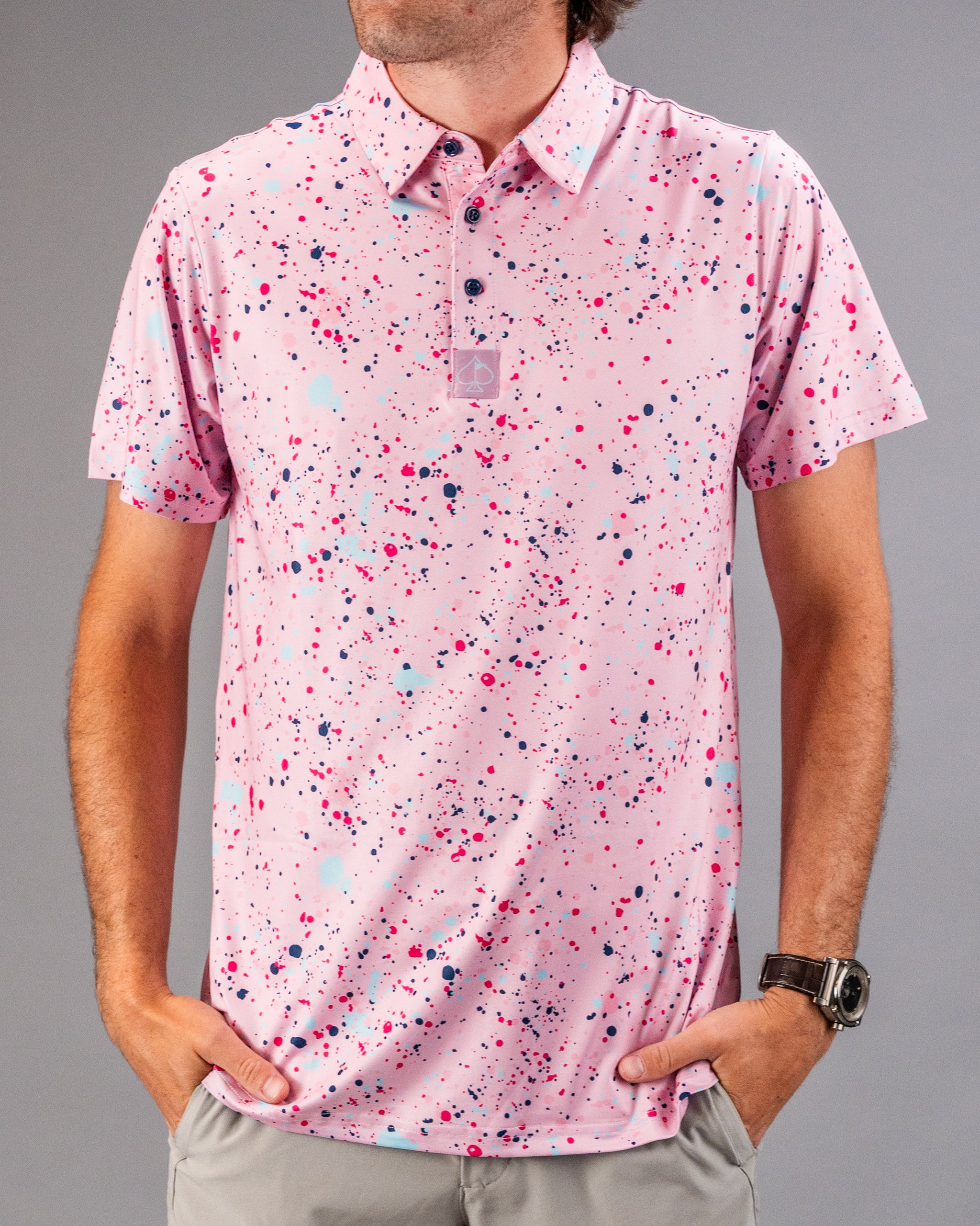 Men's pink golf polo shirt featuring a vibrant splatter pattern in various colors, perfect for a bold look on the course.