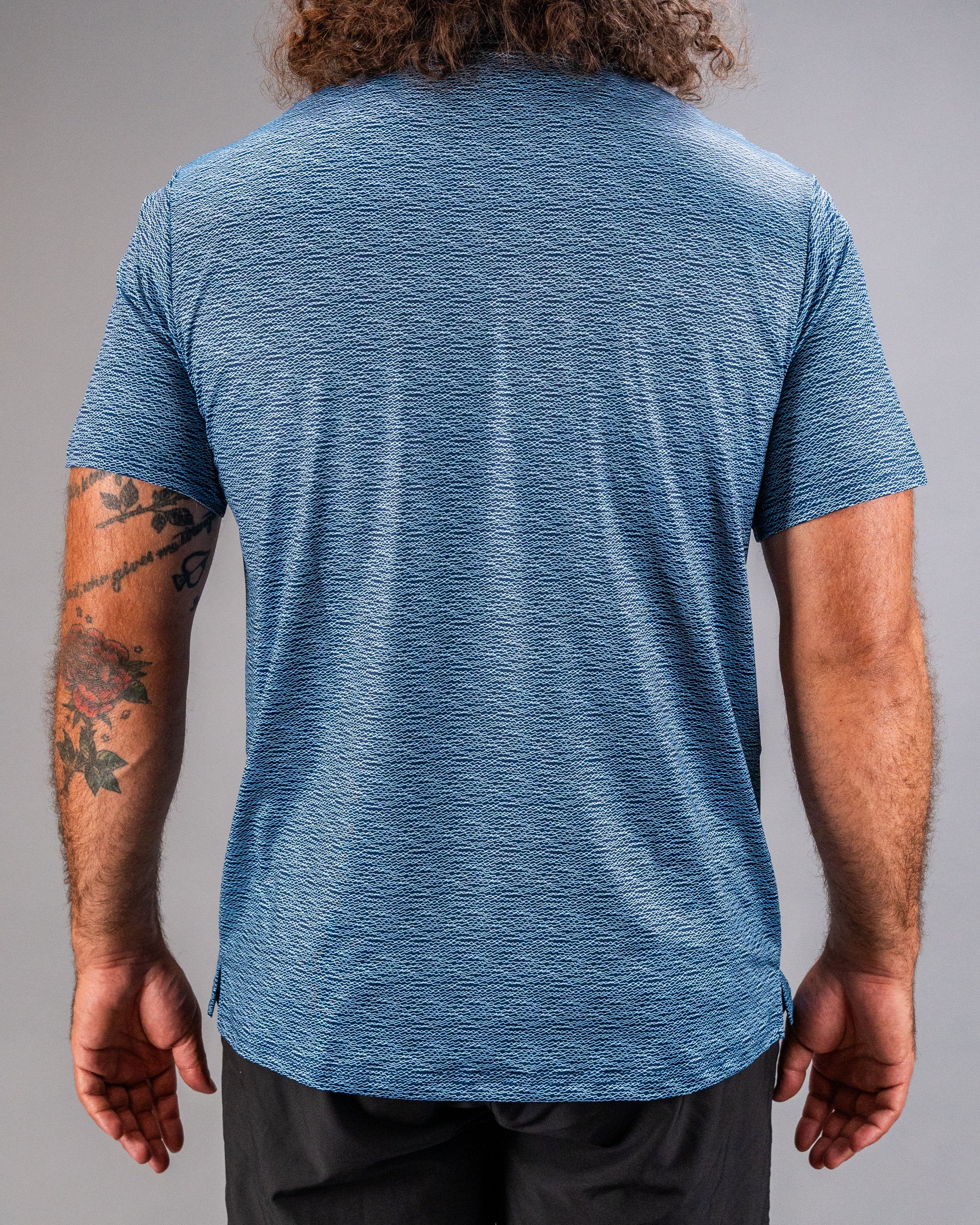 Men's blue golf shirt with a textured squiggle pattern, showcasing a relaxed fit and short sleeves from the back view.
