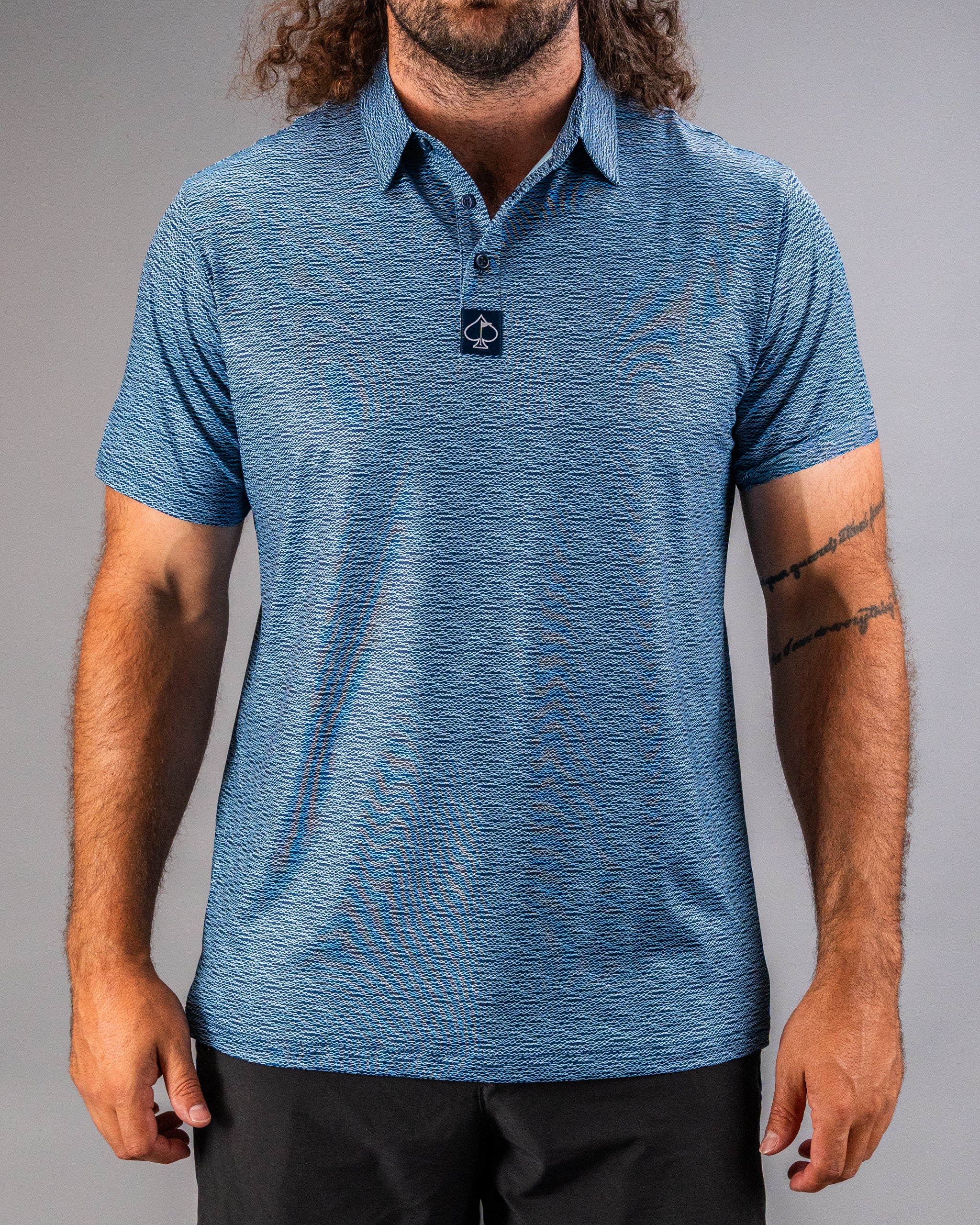 Men's blue golf polo shirt featuring a textured squiggle pattern and a logo on the collar, perfect for stylish play on the course.