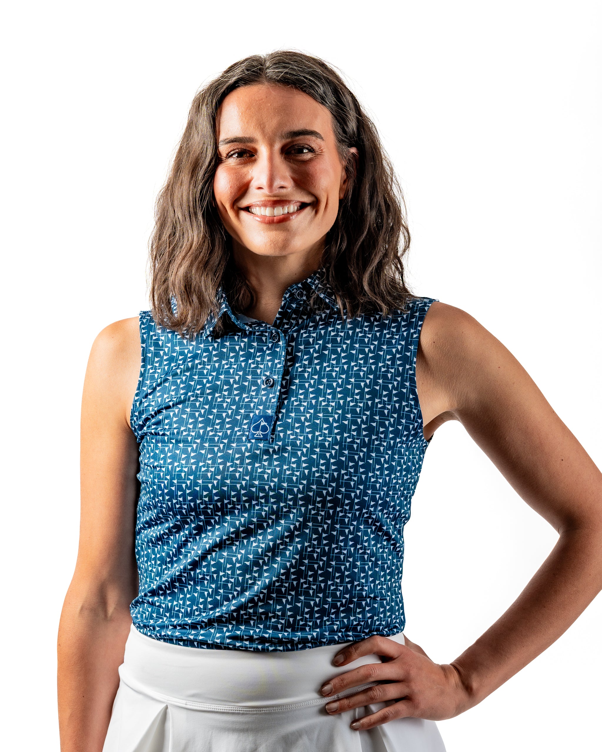 Navy and white women's golf polo featuring a flag stick pattern, modeled by a smiling woman with wavy hair.