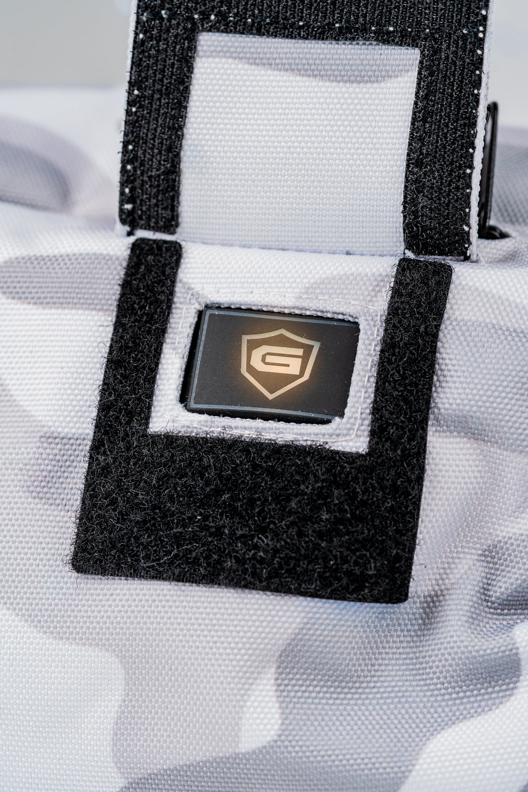 Close-up of the Pins and Aces X G-Tech Electric Hand Warmer featuring a sleek design and secure fastening strap.