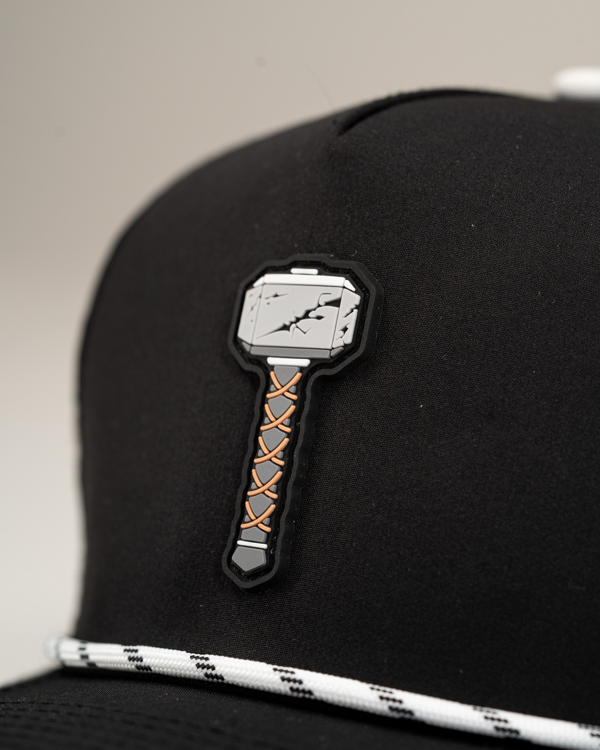 Black perforated rope hat featuring a detailed Thor's Hammer patch on the front, perfect for bold golf style.
