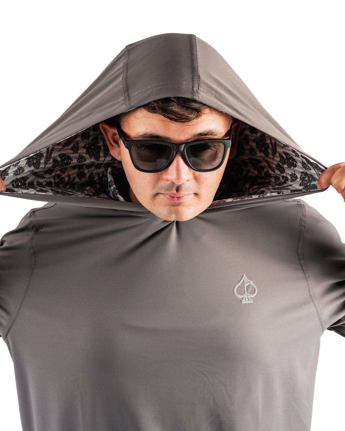 Man wearing a gray performance golf hoodie with a hood up, showcasing a unique patterned lining and sunglasses.