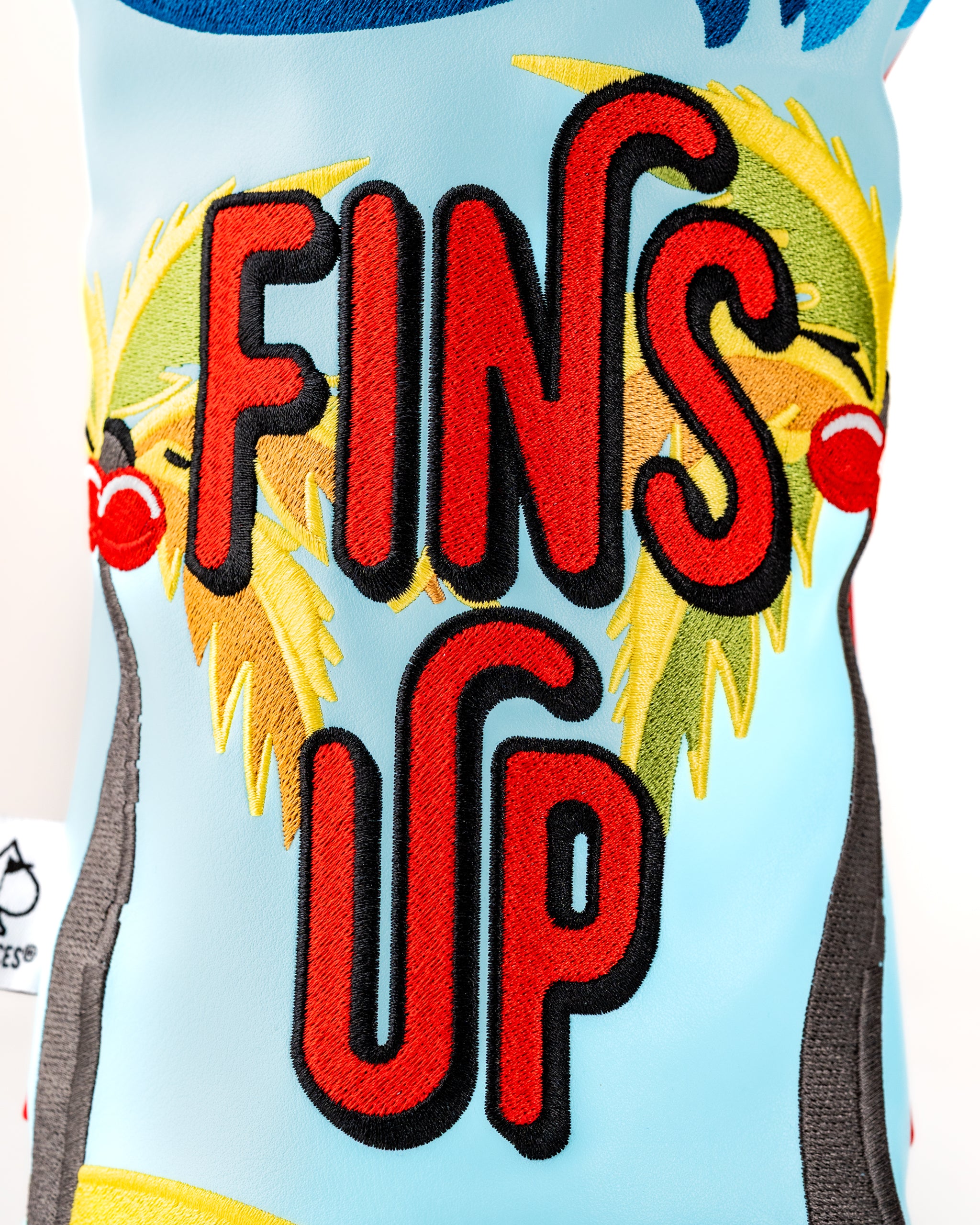 Margaritaville x Pins & Aces headcover set featuring vibrant colors and "FINS UP" embroidery with palm tree accents.