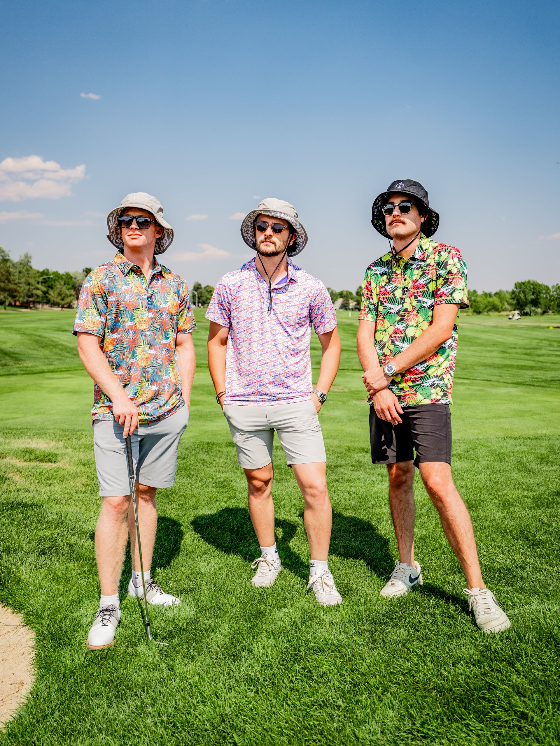 Three golfers stand on a lush green course, wearing vibrant Margaritaville shirts and bucket hats, exuding a relaxed, fun vibe.