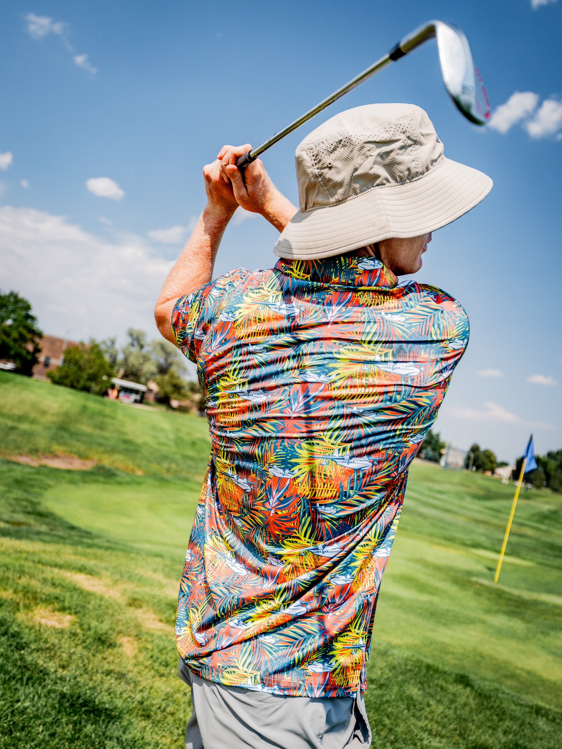 Colorful Margaritaville Bama Breeze golf shirt worn by a golfer swinging a club on a sunny course.