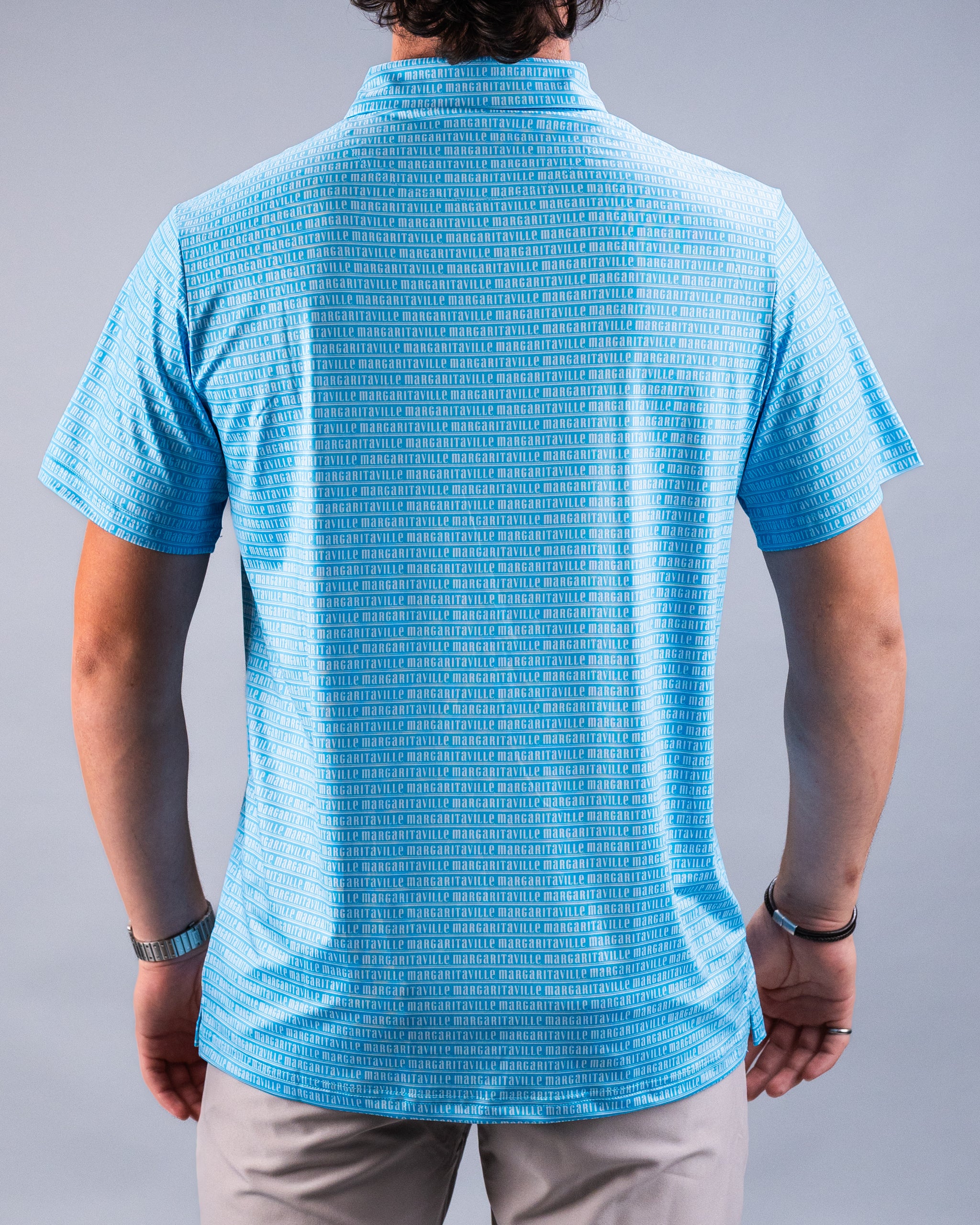 Blue golf shirt with repeating "Margaritaville" text pattern, tailored fit, short sleeves, and classic collar.