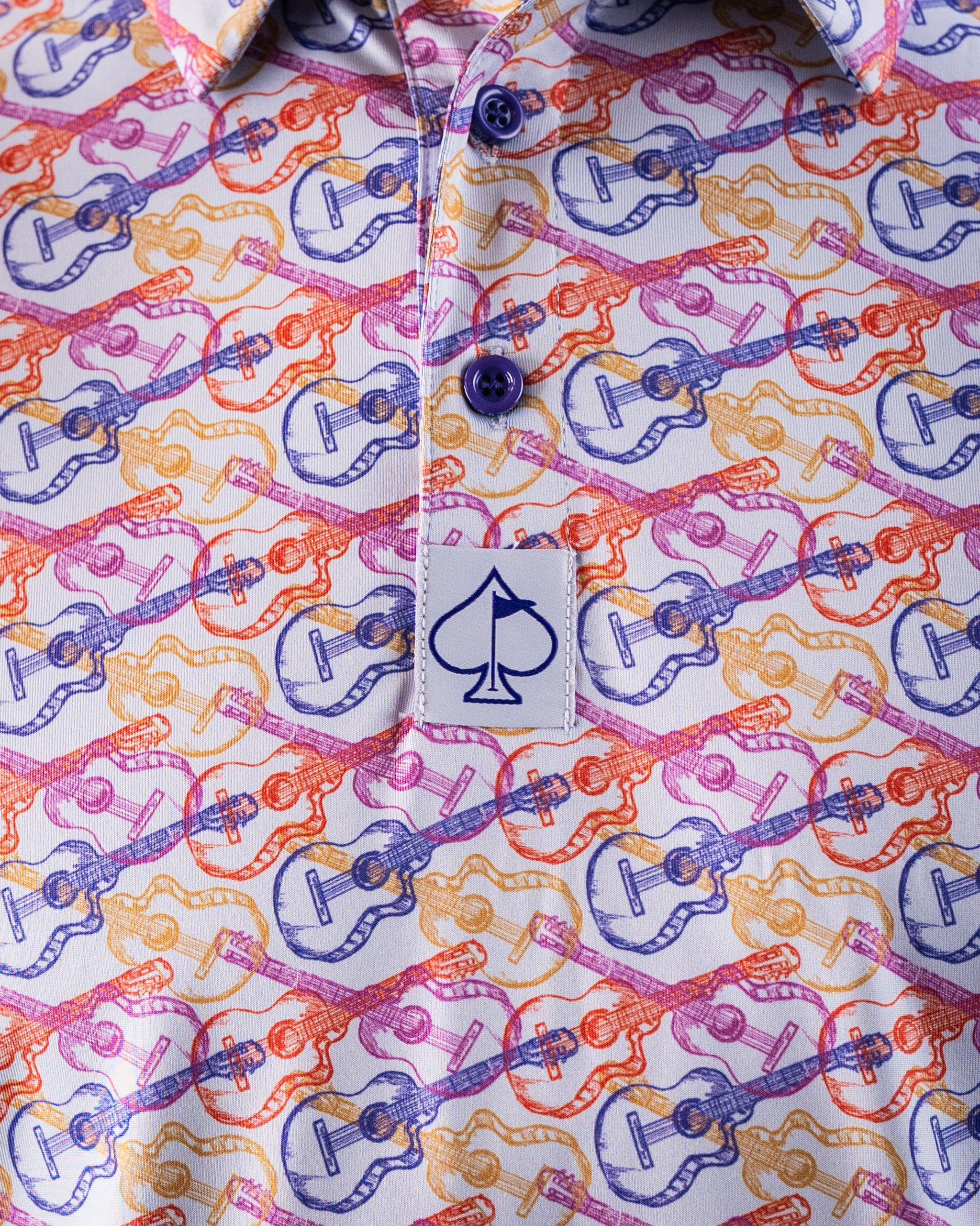 Colorful golf shirt with a pattern of pink, purple, orange, and yellow guitars, featuring a spade logo on the chest.