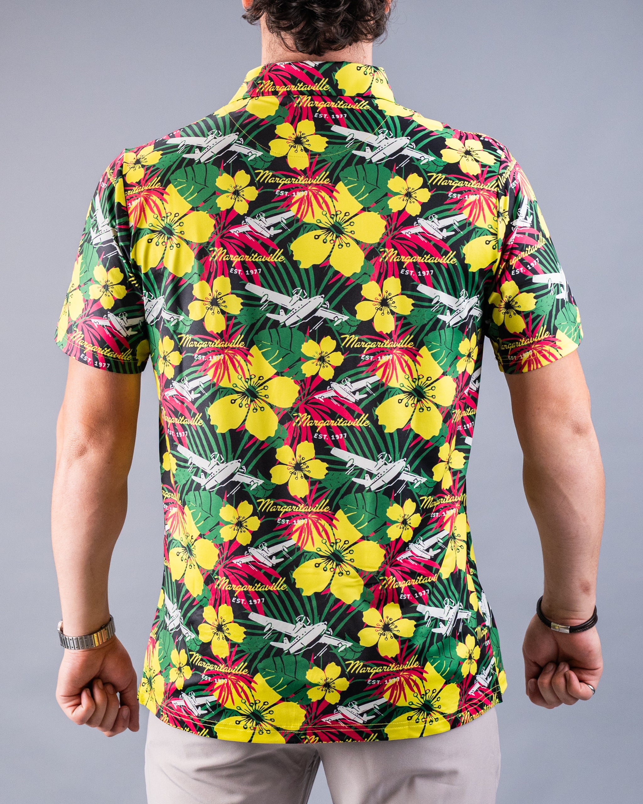 Colorful men's Hawaiian shirt with yellow hibiscus, green leaves, pink accents, and white aircraft, promoting bold, unique...