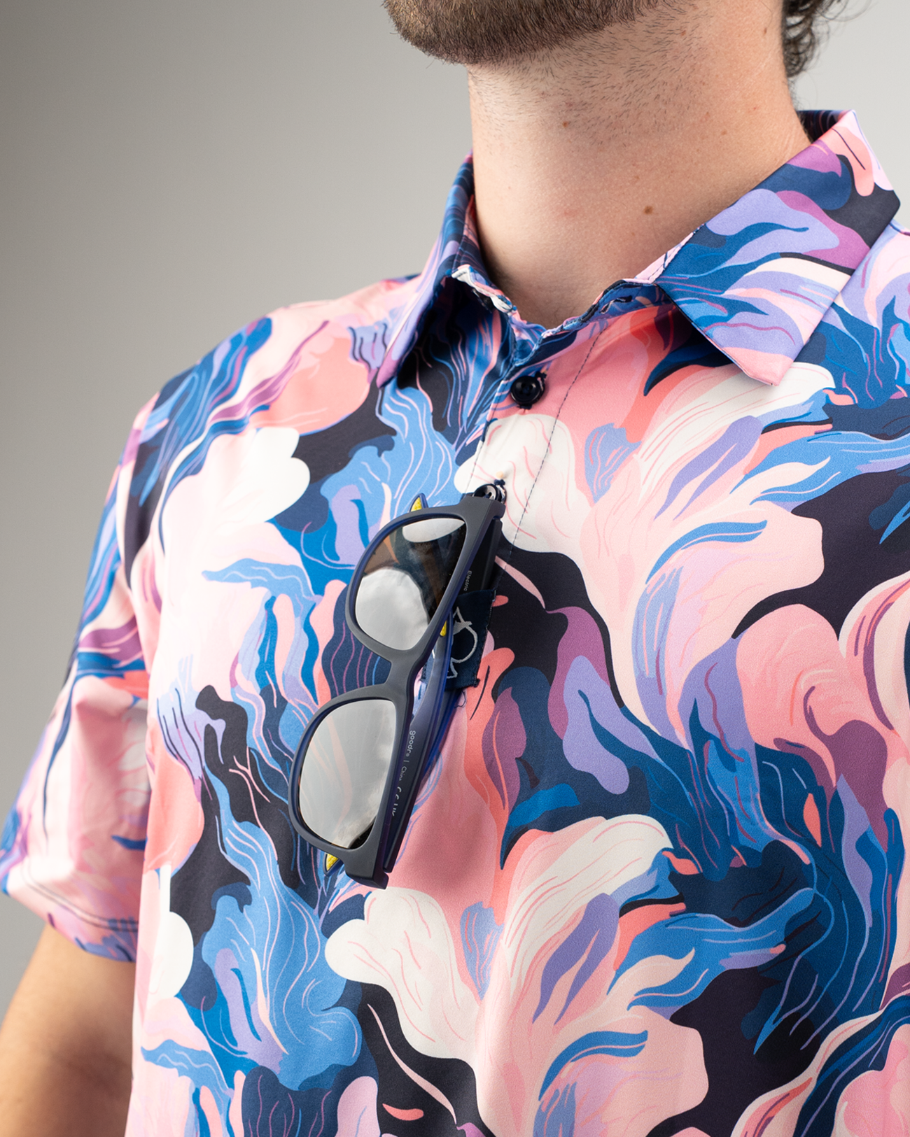 Men's Melting Floral golf shirt featuring vibrant pink and blue floral patterns, with sunglasses hanging from the collar.