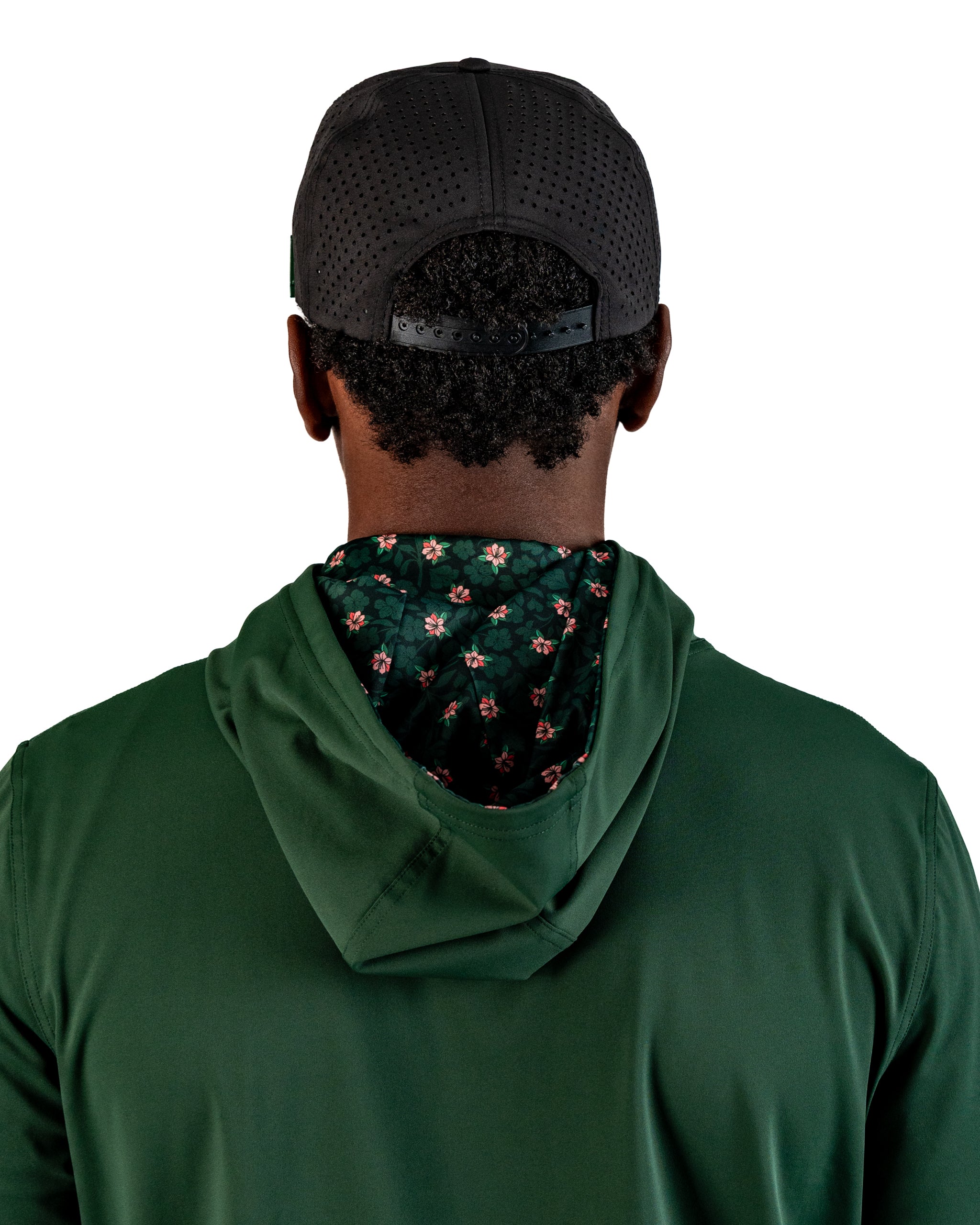 Back view of a golfer wearing a dark azalea performance hoodie with a floral-lined hood, paired with a black cap.
