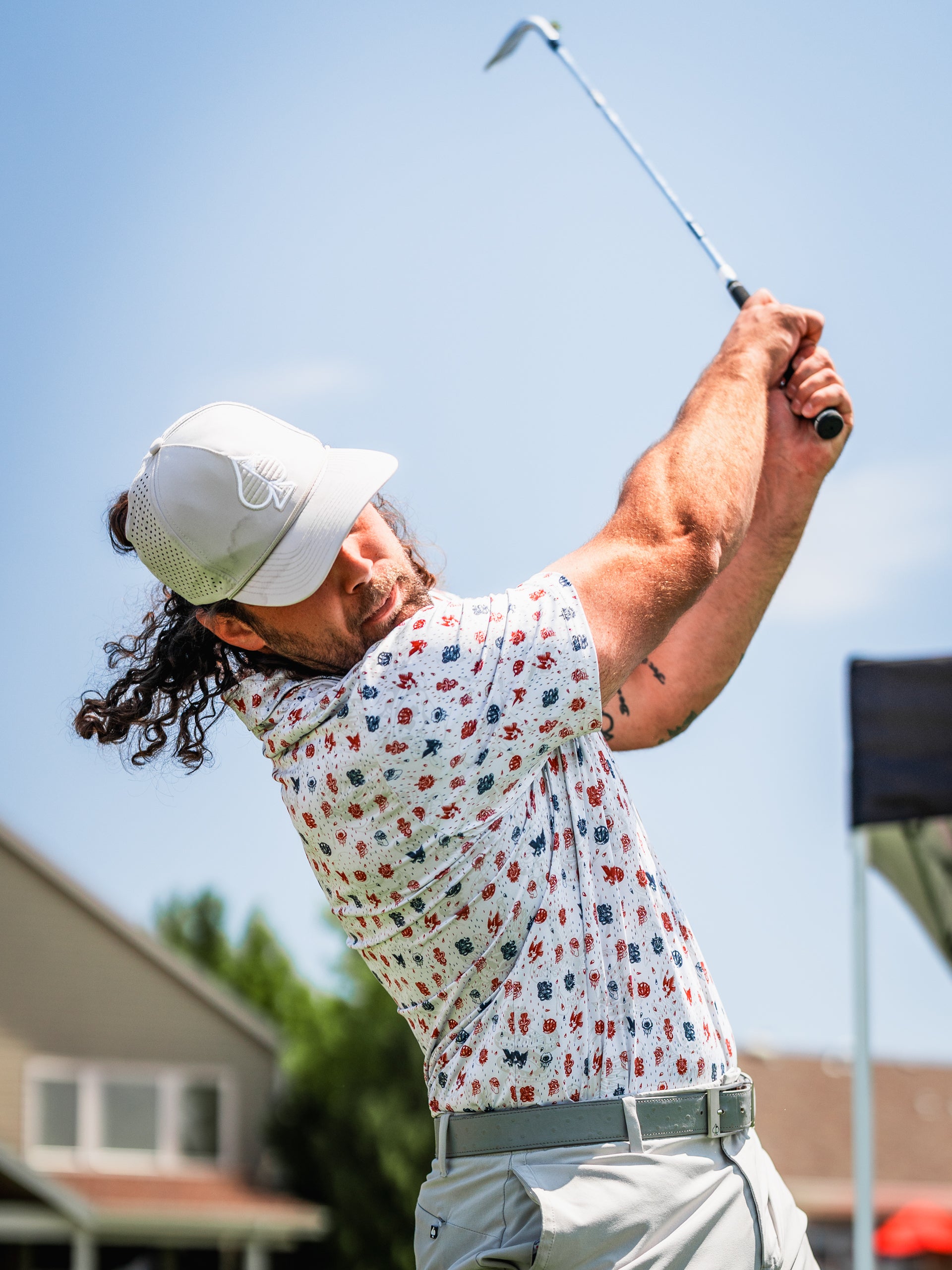 A golfer swings a club while wearing a floral-patterned shirt from the American Traditional collection.