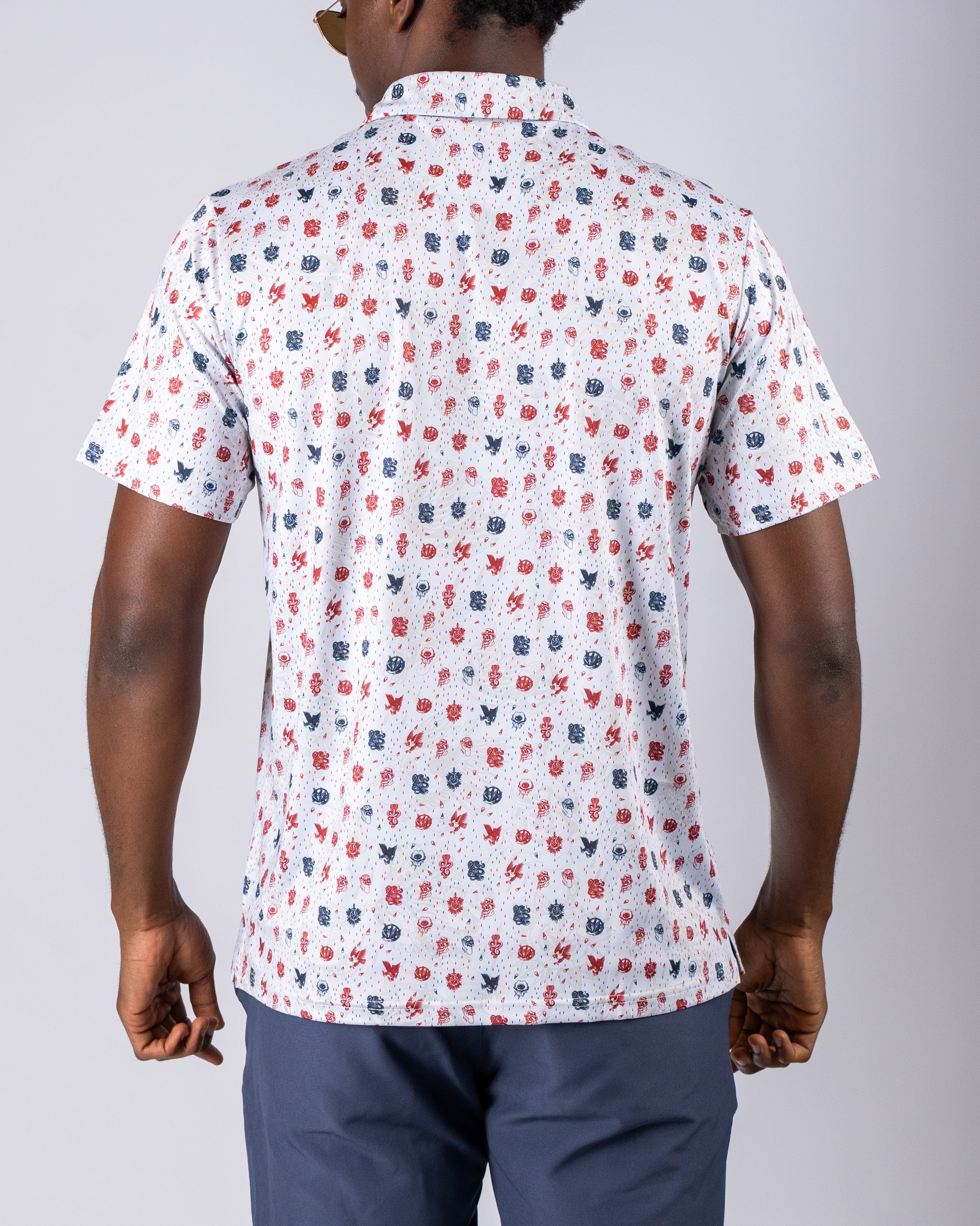 Men's American Traditional golf shirt featuring a colorful pattern of red, blue, and white designs on a light background.
