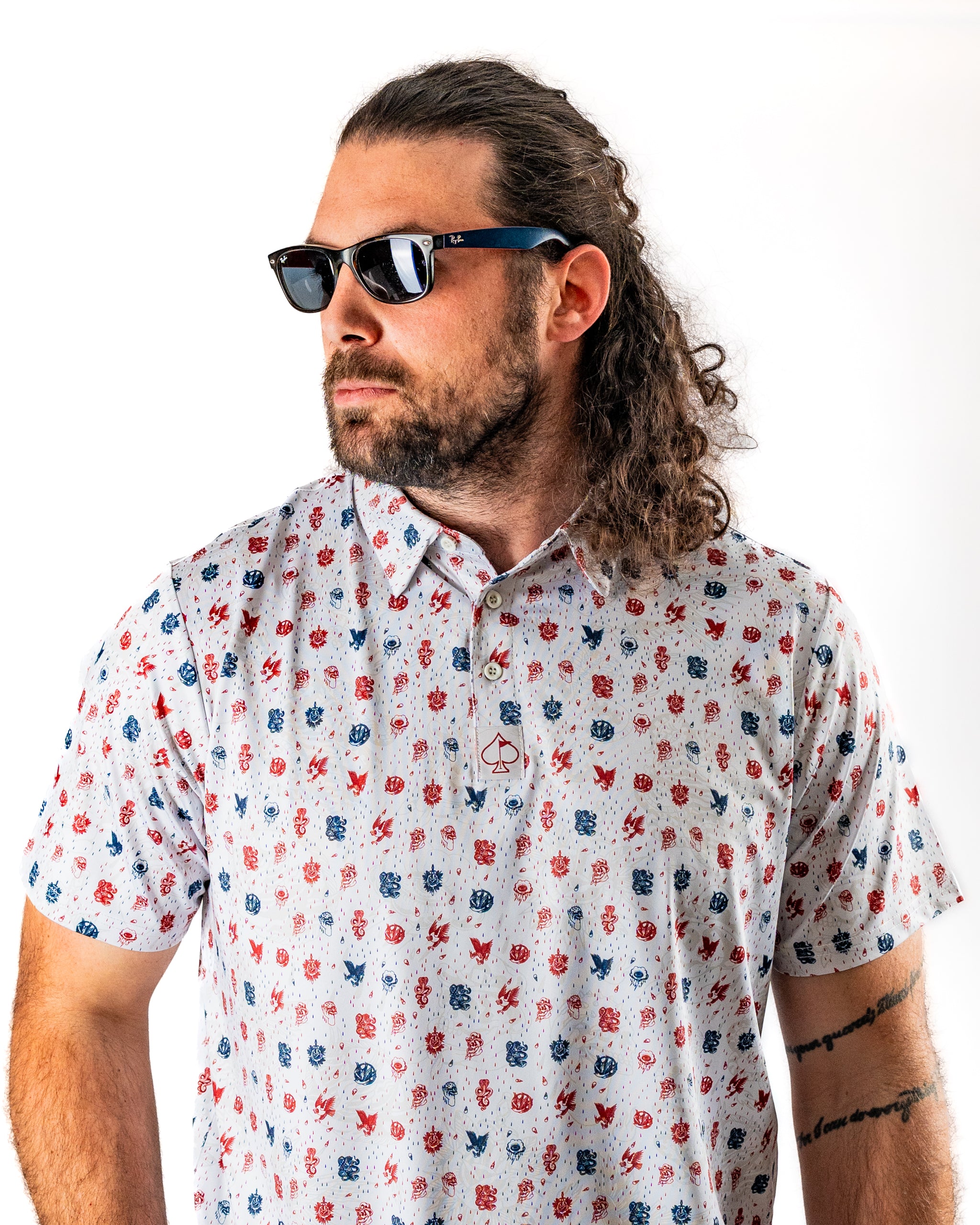Man wearing an American Traditional golf polo shirt with a colorful pattern, paired with stylish sunglasses.