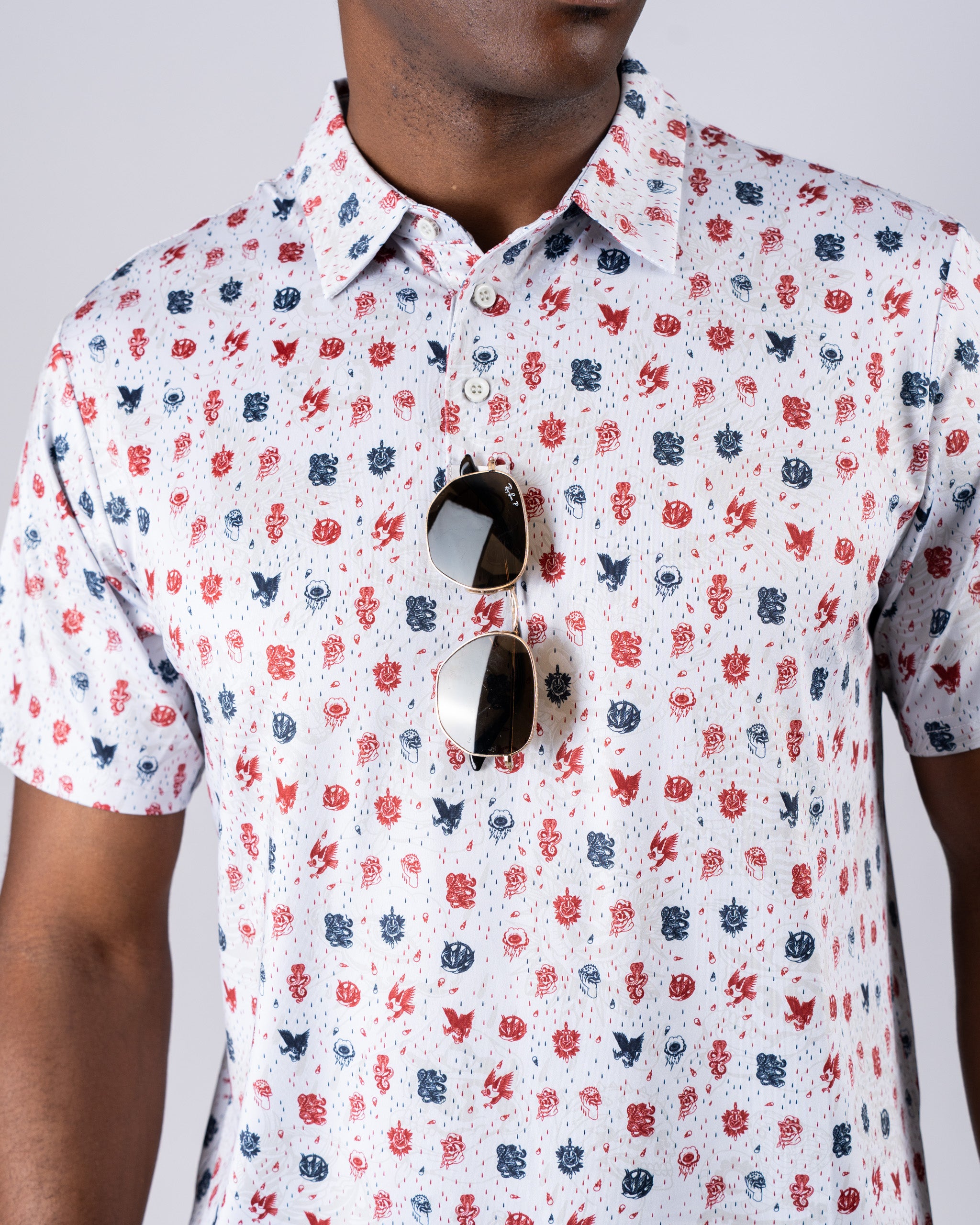 Men's American Traditional golf shirt featuring a colorful pattern of classic symbols, paired with stylish sunglasses.