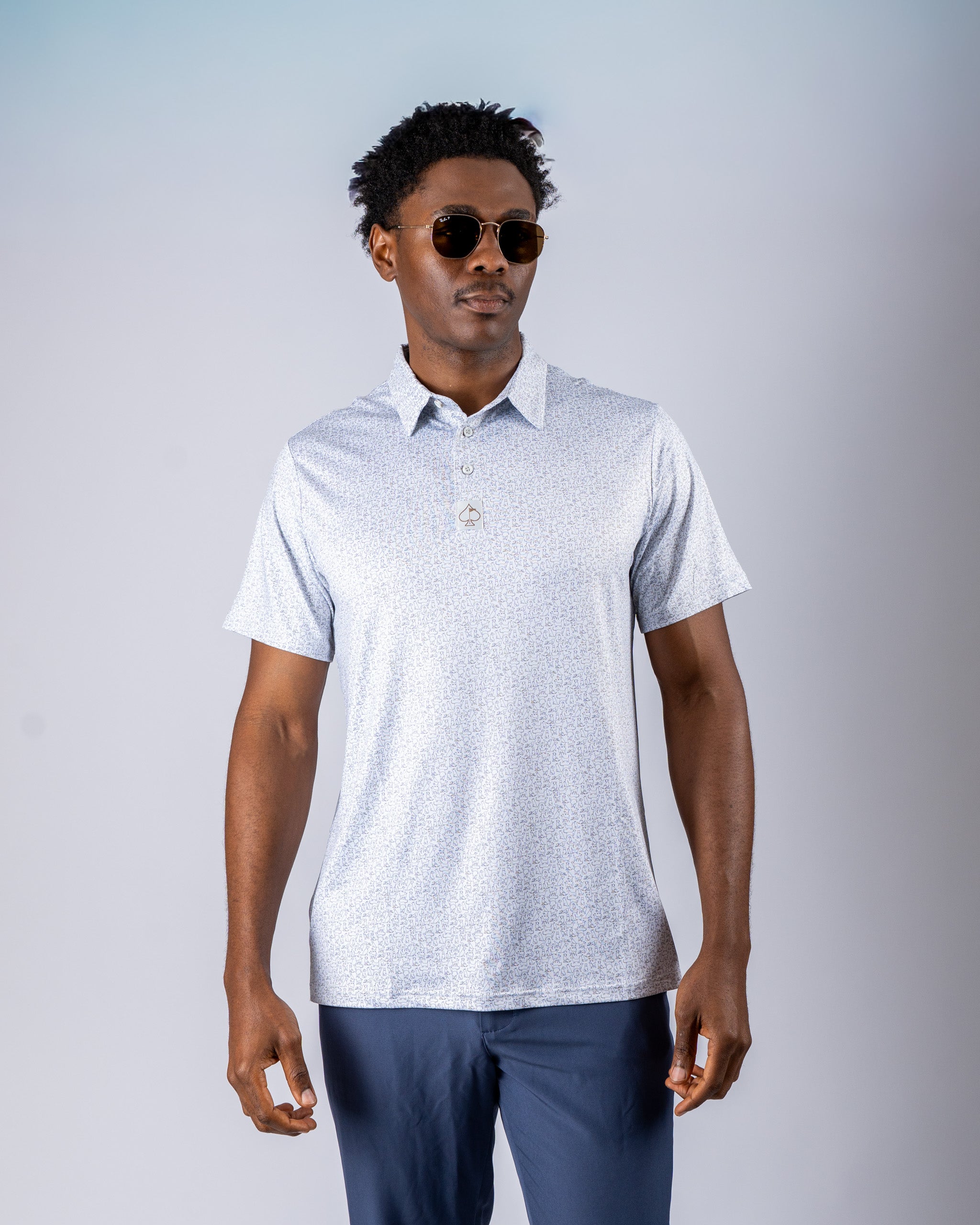 Stylish men's golf polo in light blue with a subtle pattern, paired with sunglasses for a modern look on the course.