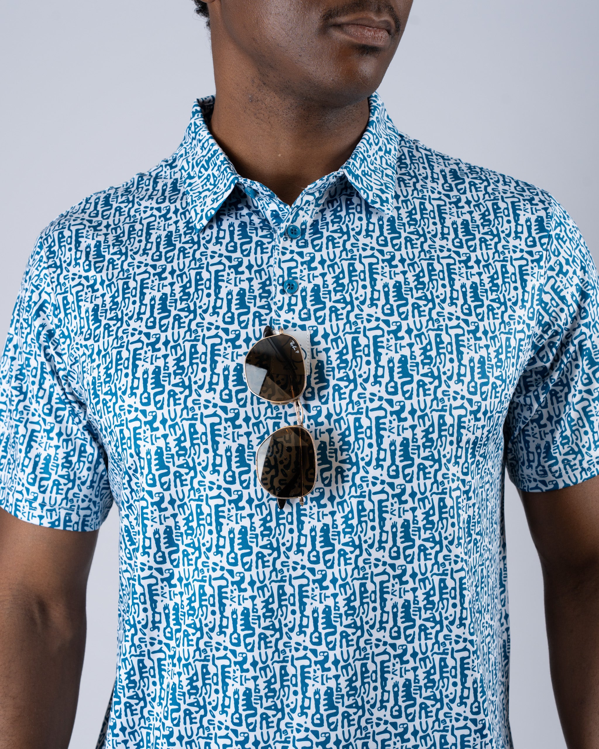 Men's Maze Craze golf shirt featuring a bold, abstract pattern in blue and white, paired with stylish sunglasses.