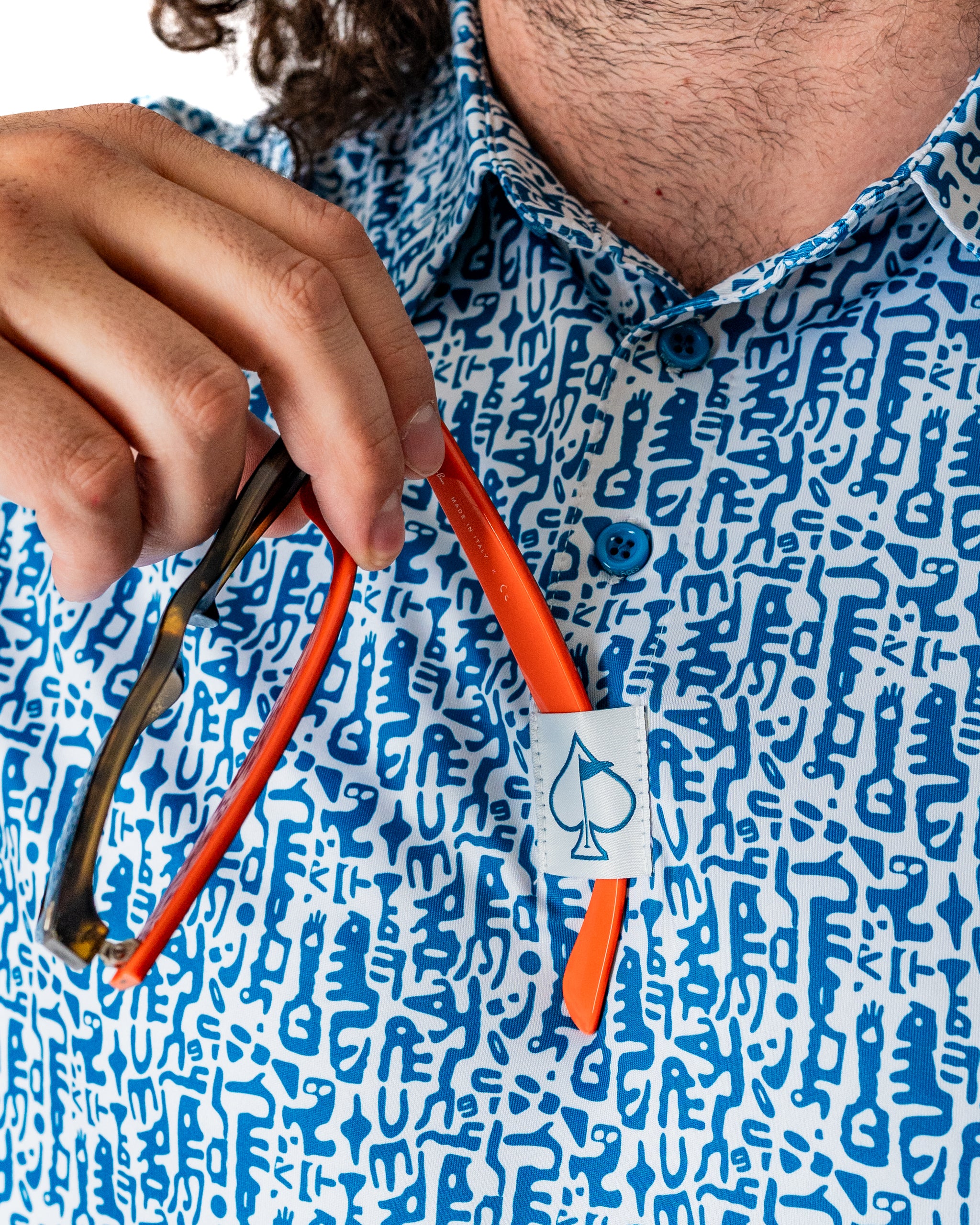 Bold blue and white patterned shirt with a unique design, featuring an orange sunglass holder on the chest pocket.