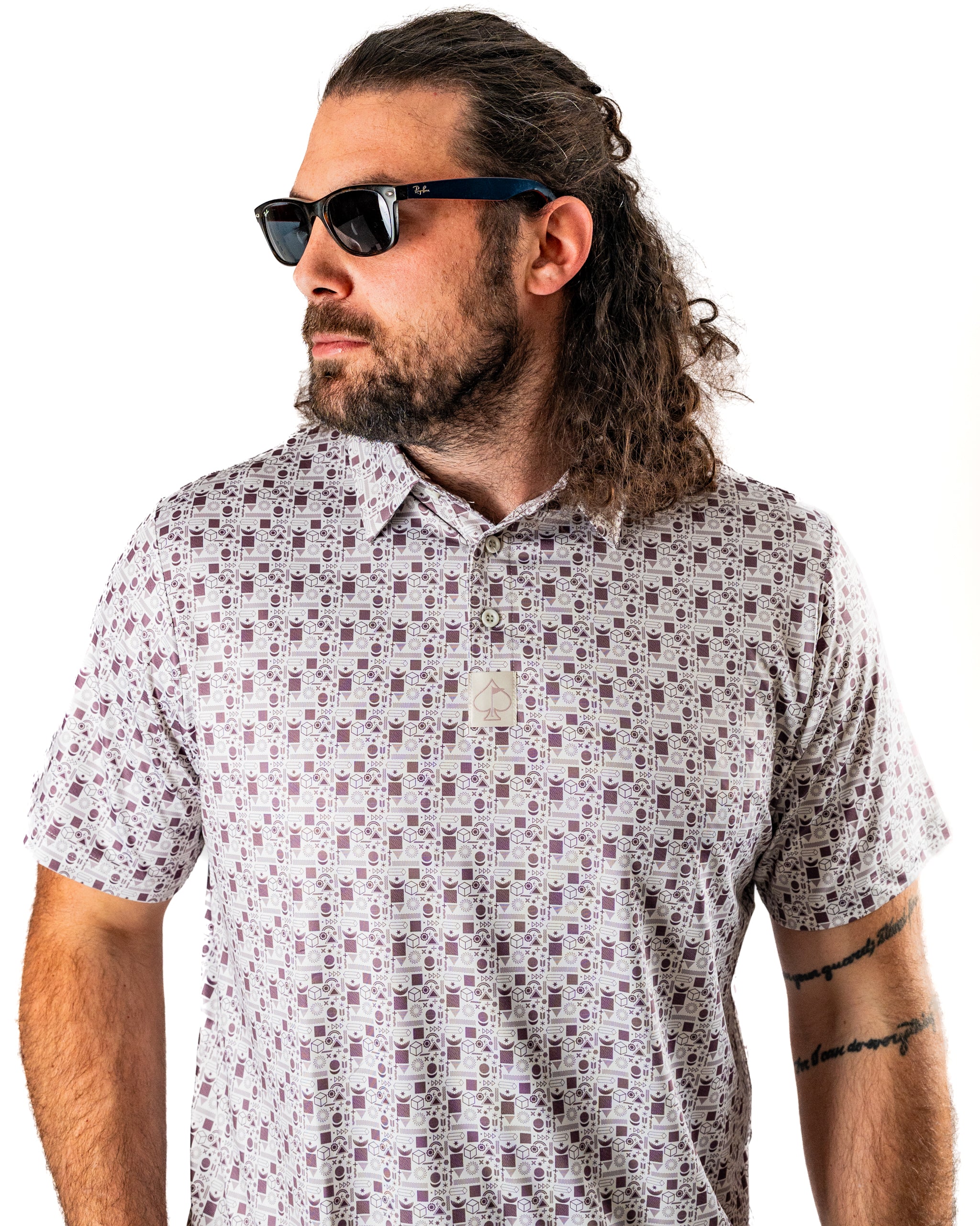 Man wearing a retro-style golf polo with a unique geometric pattern, accessorized with sunglasses.