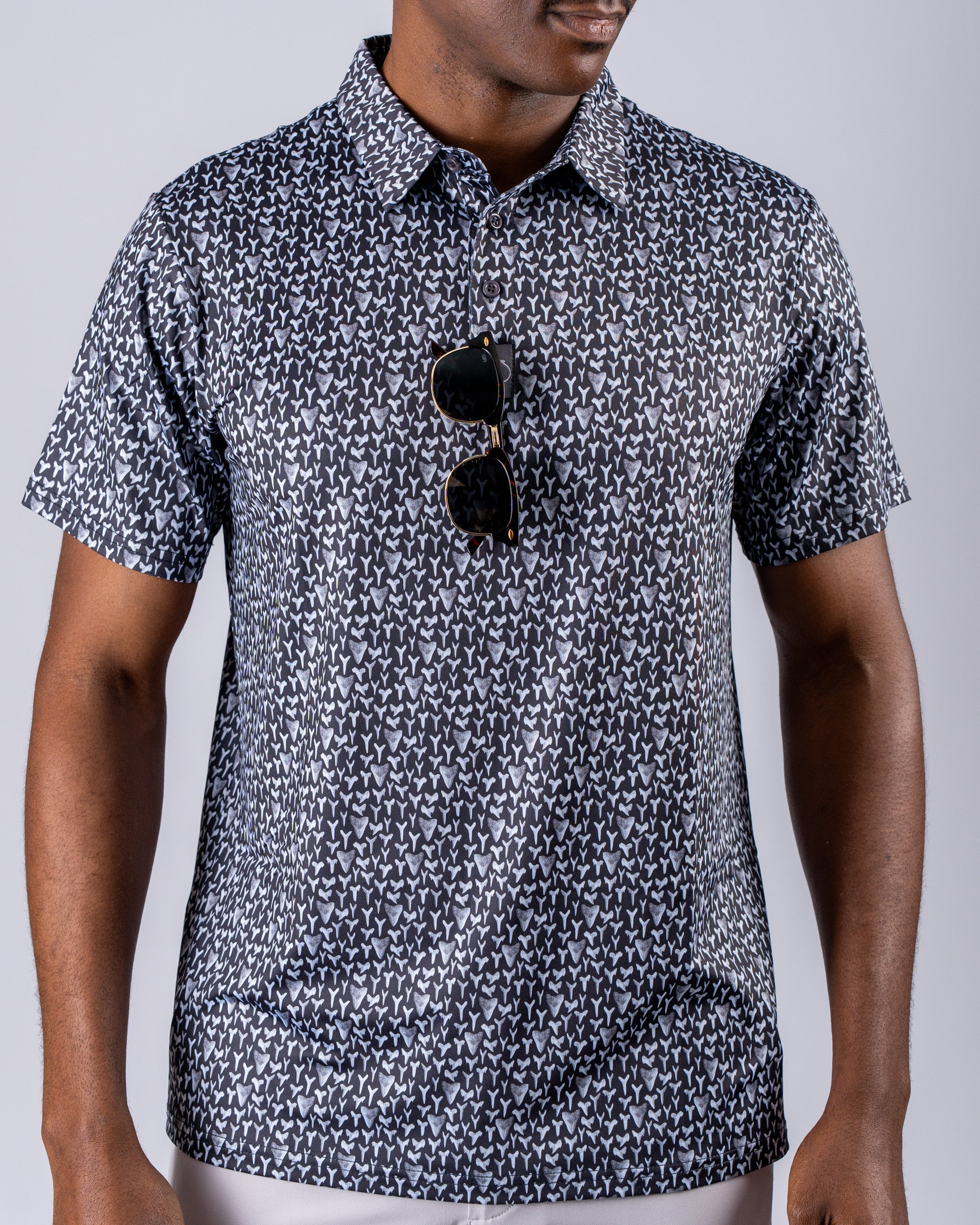 Men's golf shirt featuring a shark tooth pattern in black and white, styled with sunglasses for a bold look on the course.