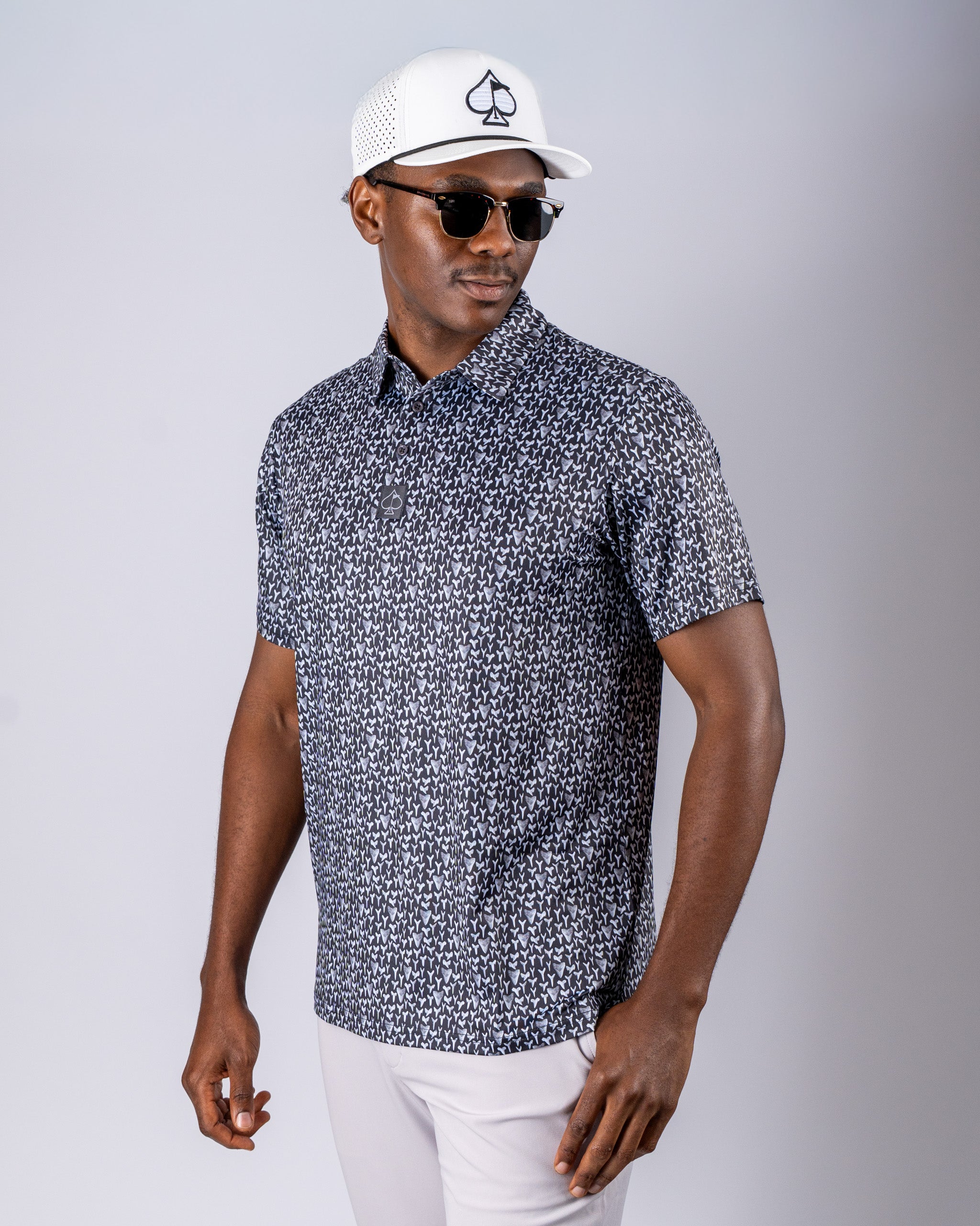 Men's golf polo shirt with a shark tooth pattern, paired with a stylish cap and sunglasses for a bold on-course look.