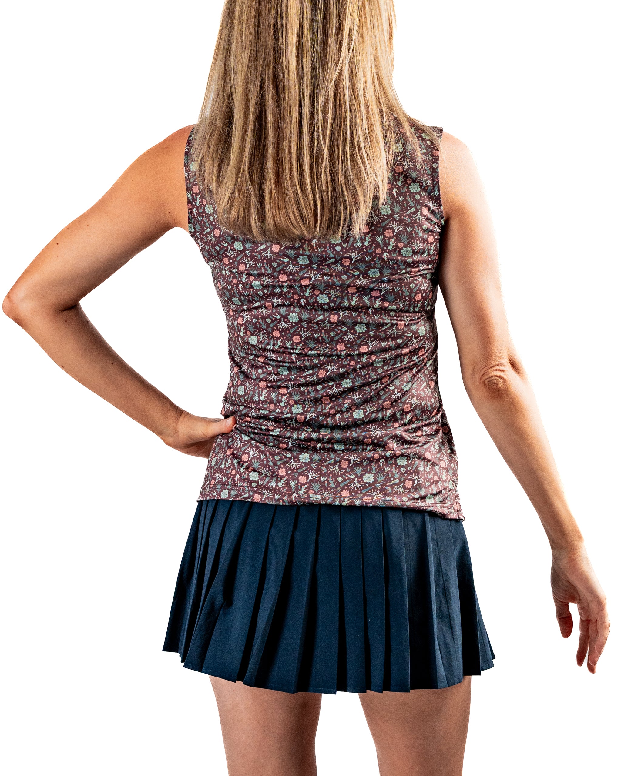 Women's Desert Sage sleeveless top with a floral pattern, paired with a pleated navy skirt, showcasing a stylish golf outfit.
