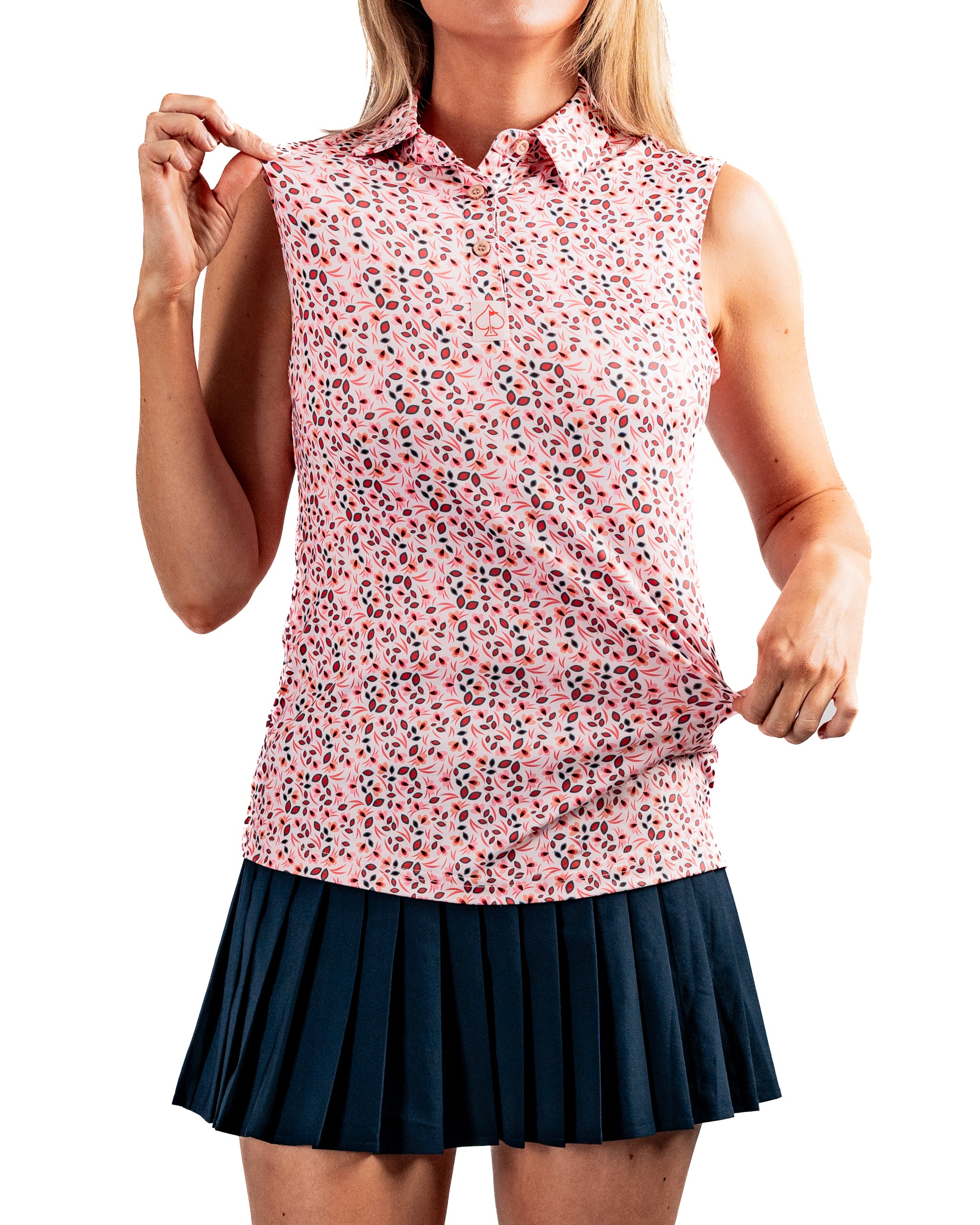 Women's Soft Spoken sleeveless golf polo in a floral print, paired with a navy pleated skirt, showcasing a stylish and comfortable fit.