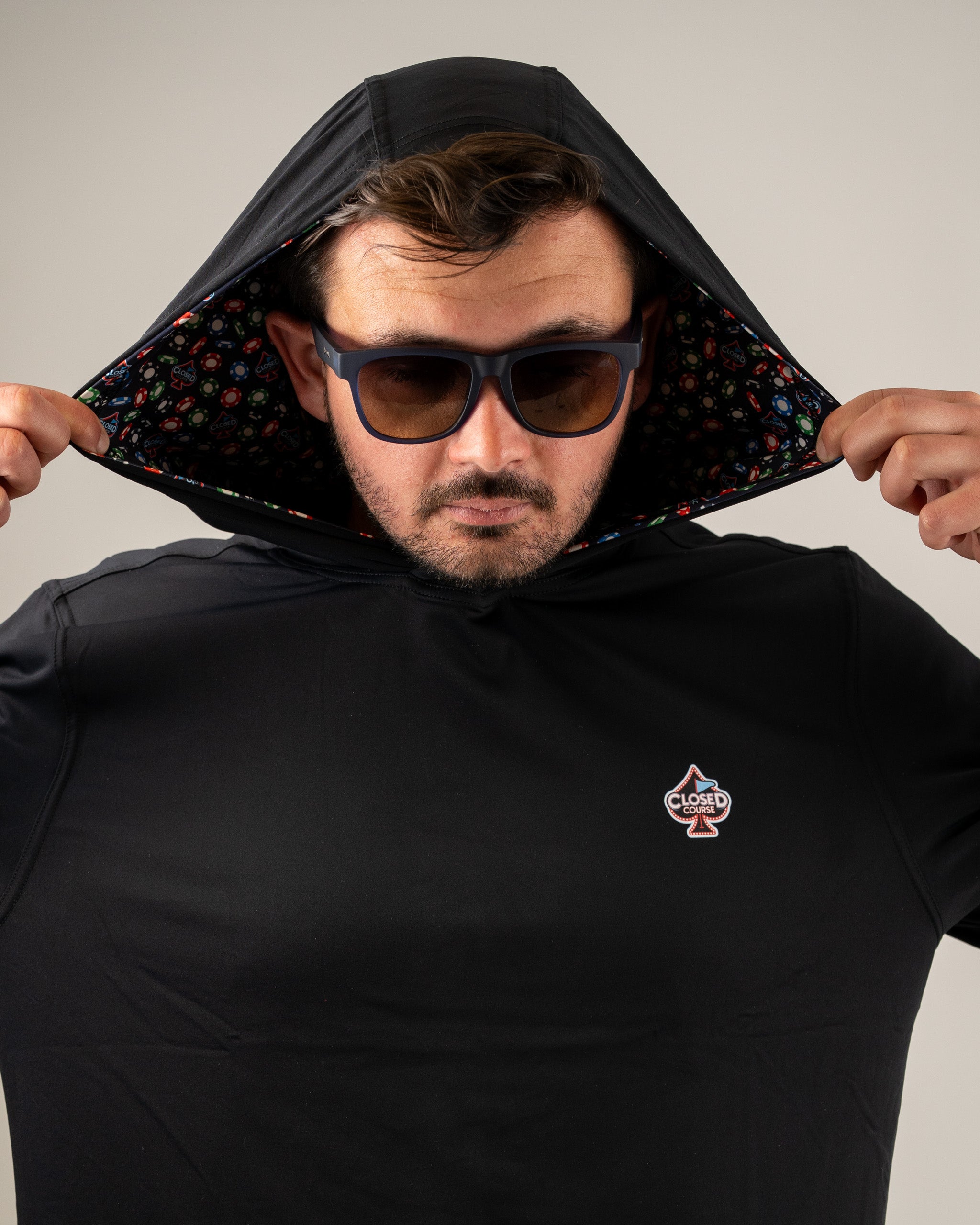 Man wearing a black performance golf hoodie with a colorful patterned lining, showcasing a stylish and sporty look.