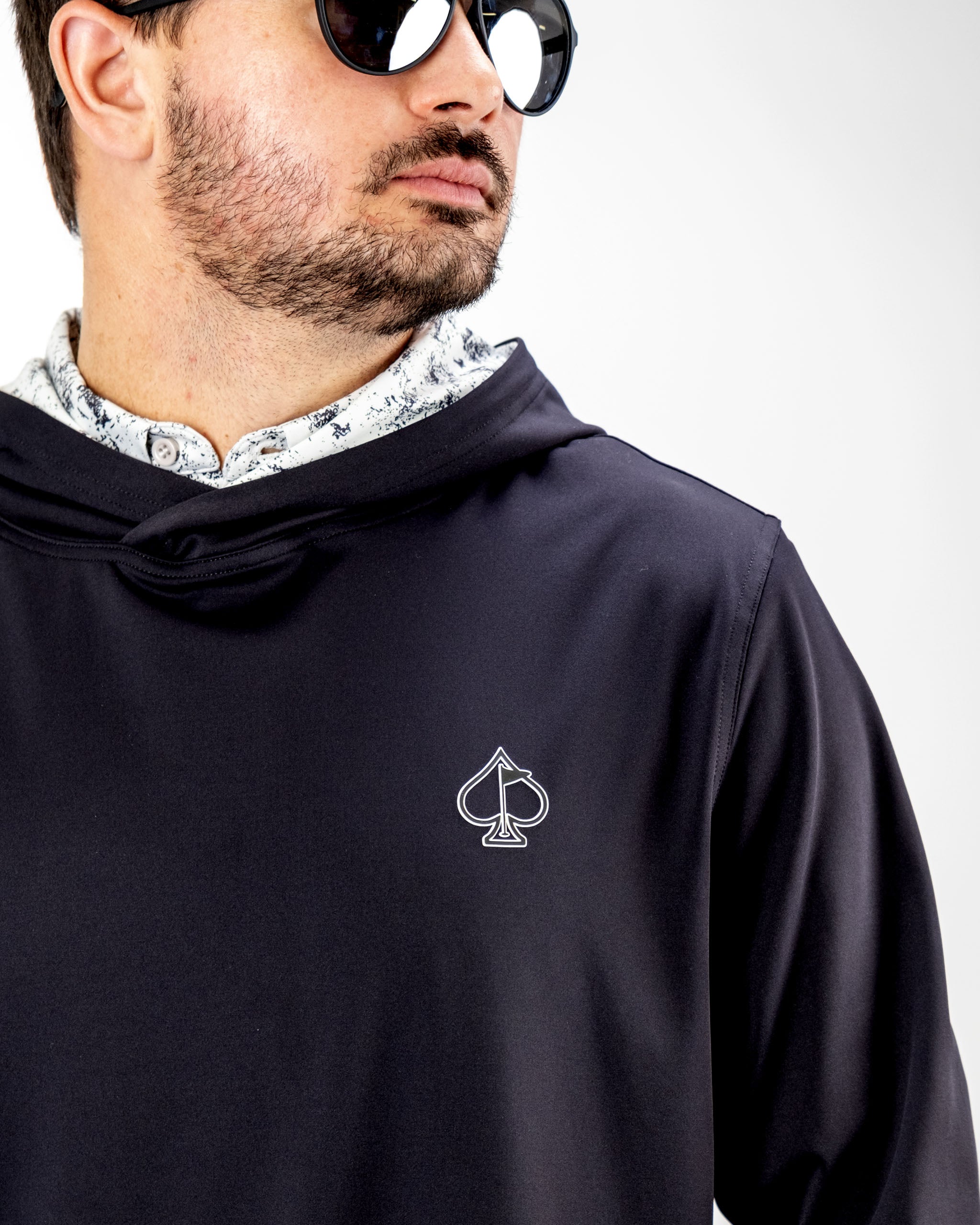 Men's performance golf hoodie in dark color with spade logo, designed for comfort and style on the course.