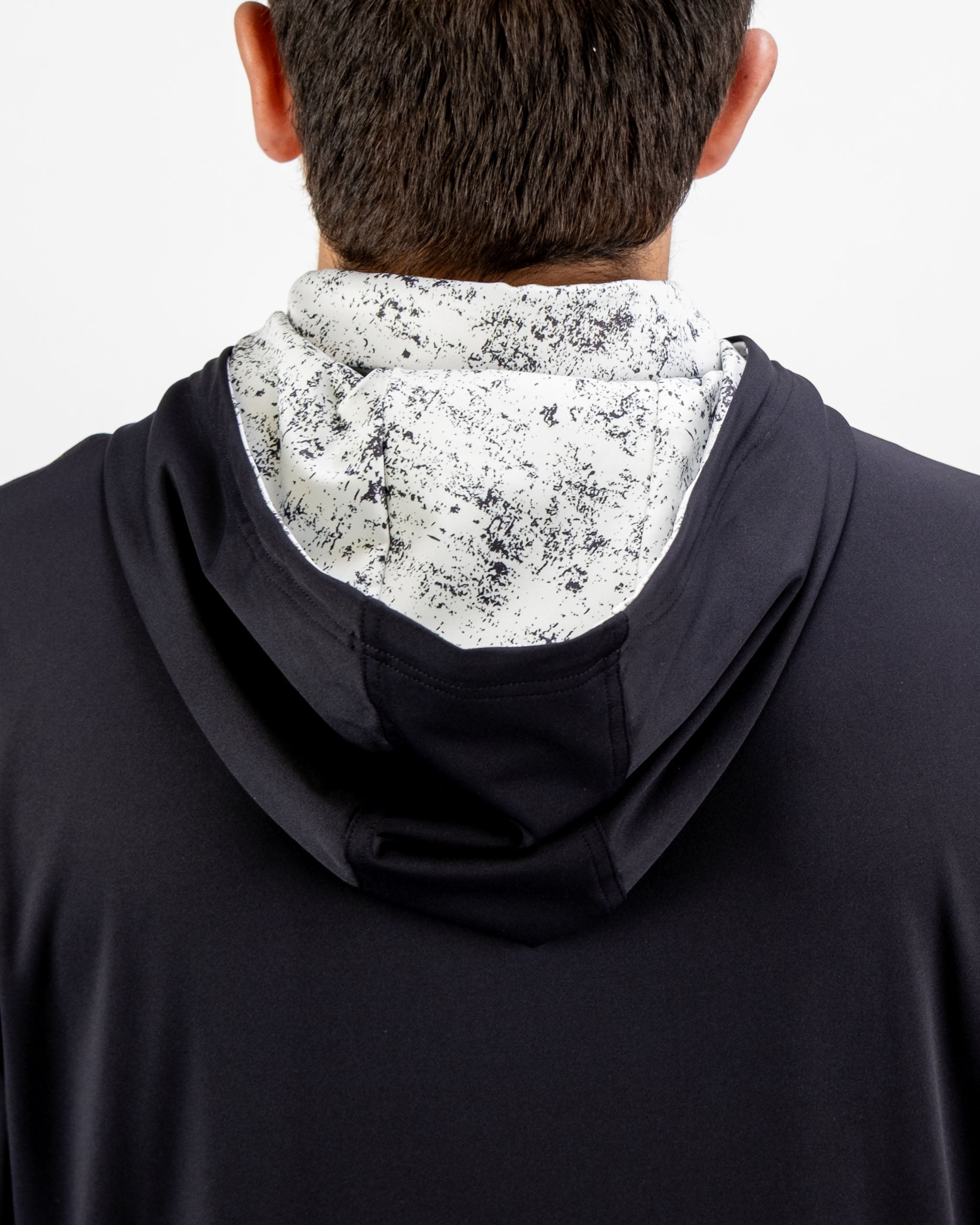 Men's performance golf hoodie in black with a white noise patterned hood, designed for comfort and style on the course.