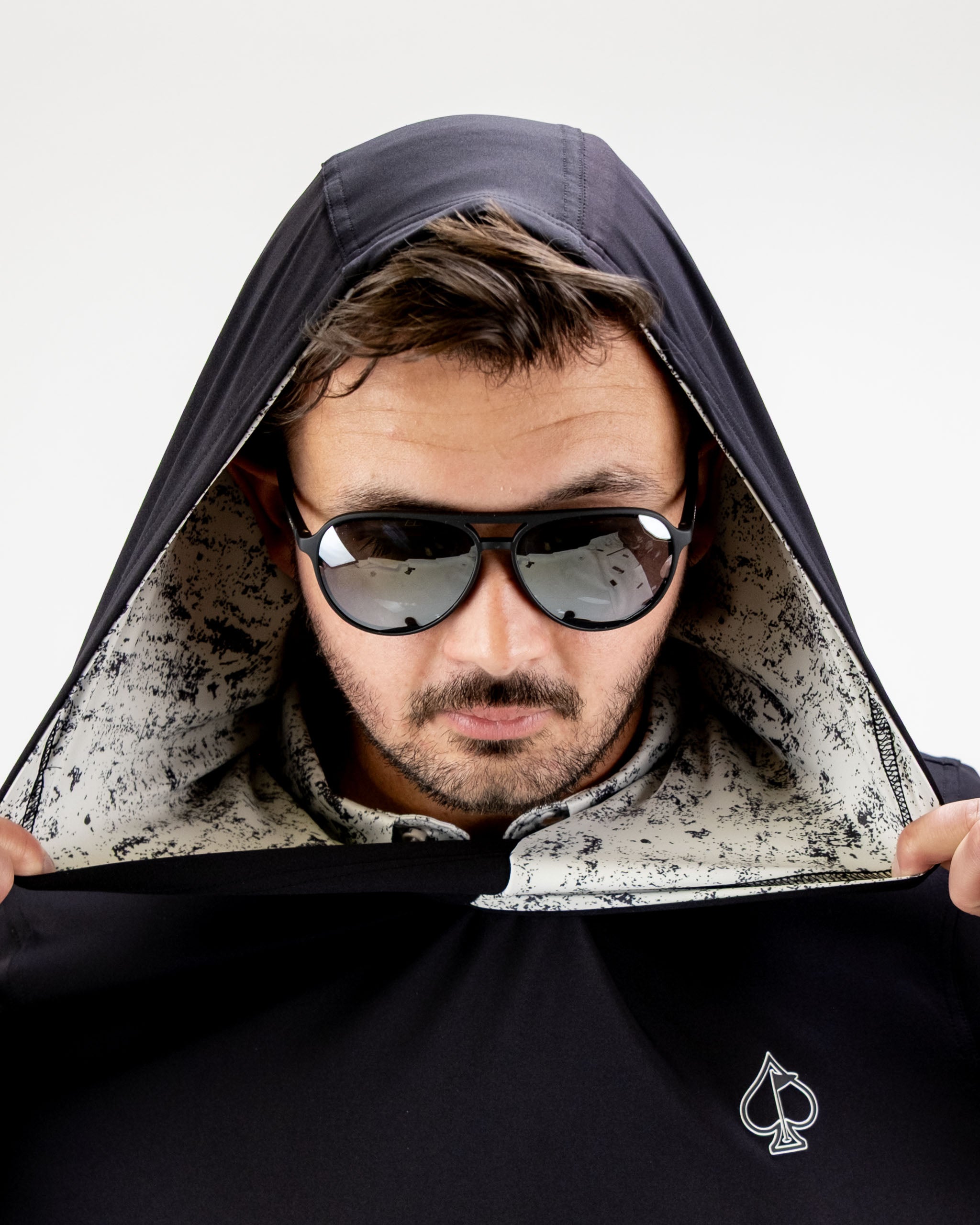 Man wearing a black performance golf hoodie with a unique patterned interior, showcasing a stylish look for golfers.