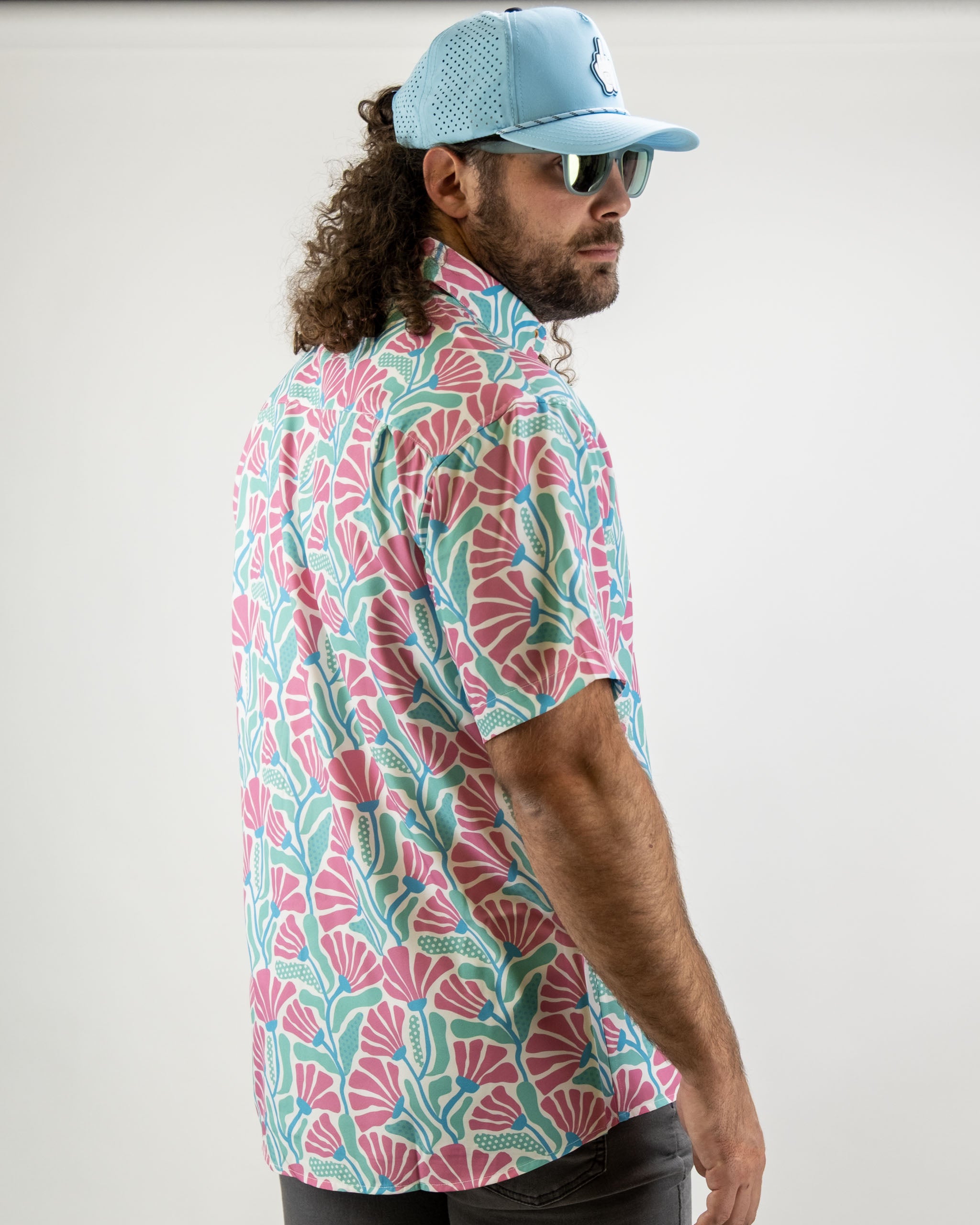 Men's short-sleeve shirt featuring a vibrant coral and teal floral pattern, perfect for stylish golf outings.