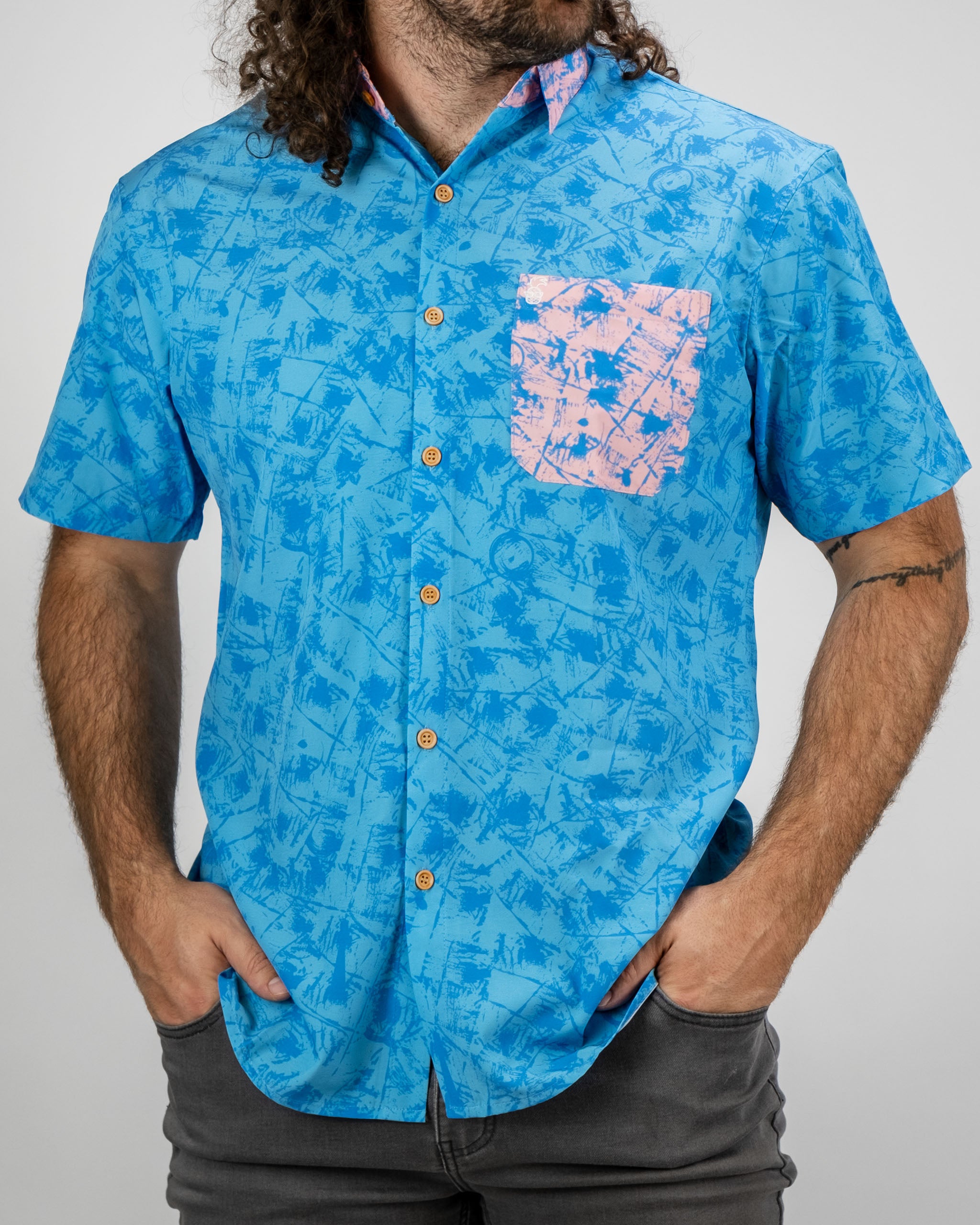 Bold blue short-sleeve shirt featuring a pastel pink pocket and a playful abstract pattern, perfect for stylish golfers.