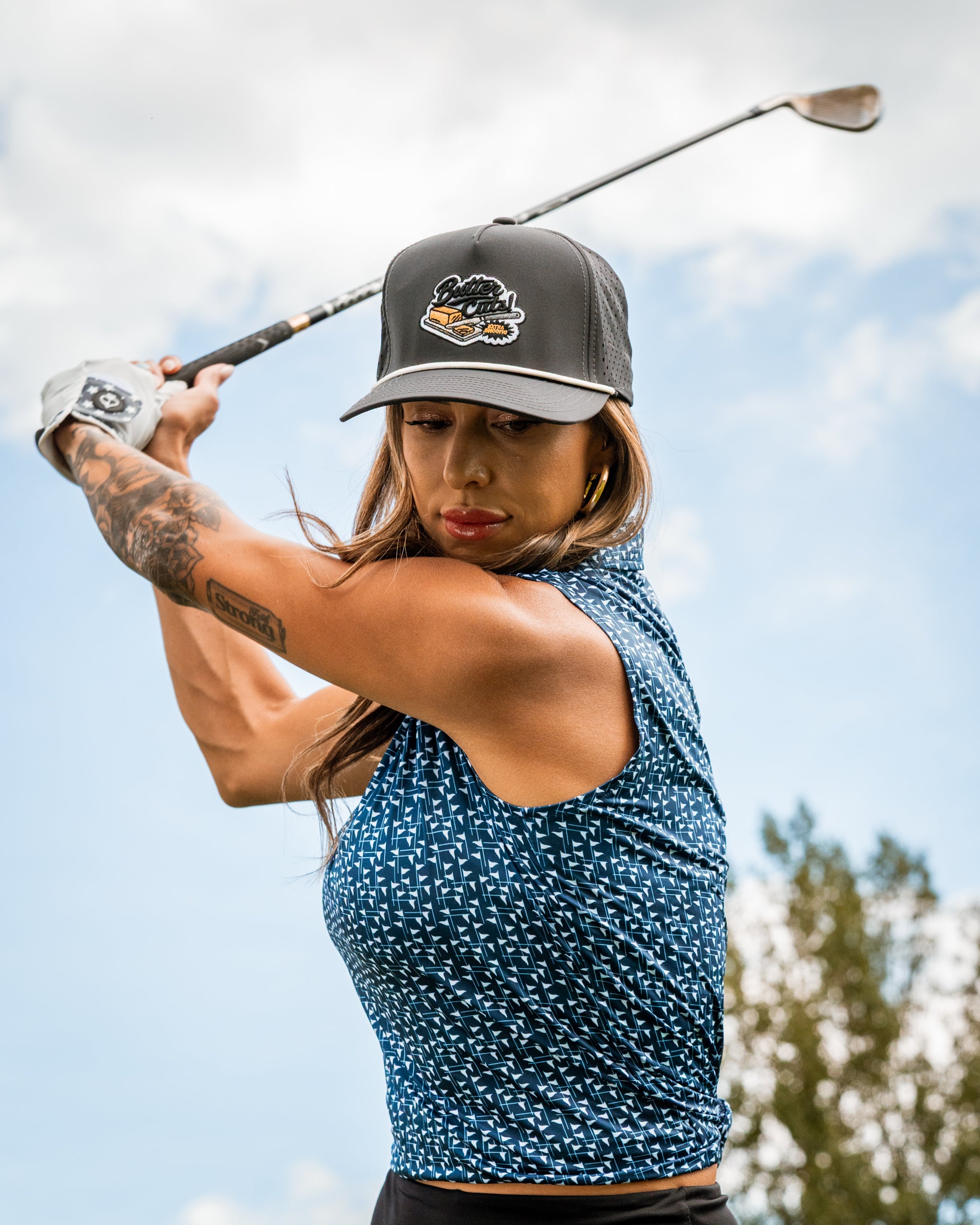 Navy and white women's golf shirt with a stylish design, worn by a woman swinging a golf club outdoors.