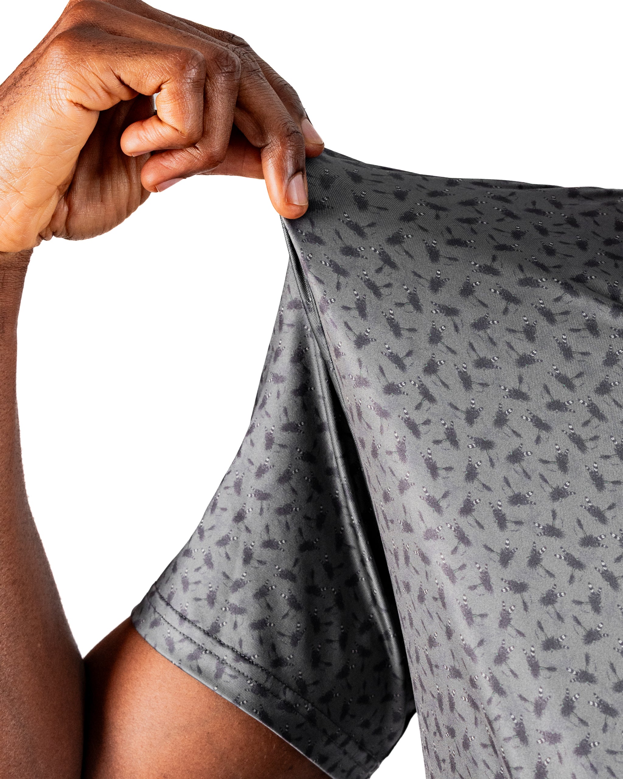 Close-up of a hand pulling the sleeve of a lightweight, patterned golf shirt, showcasing its flexibility and design.
