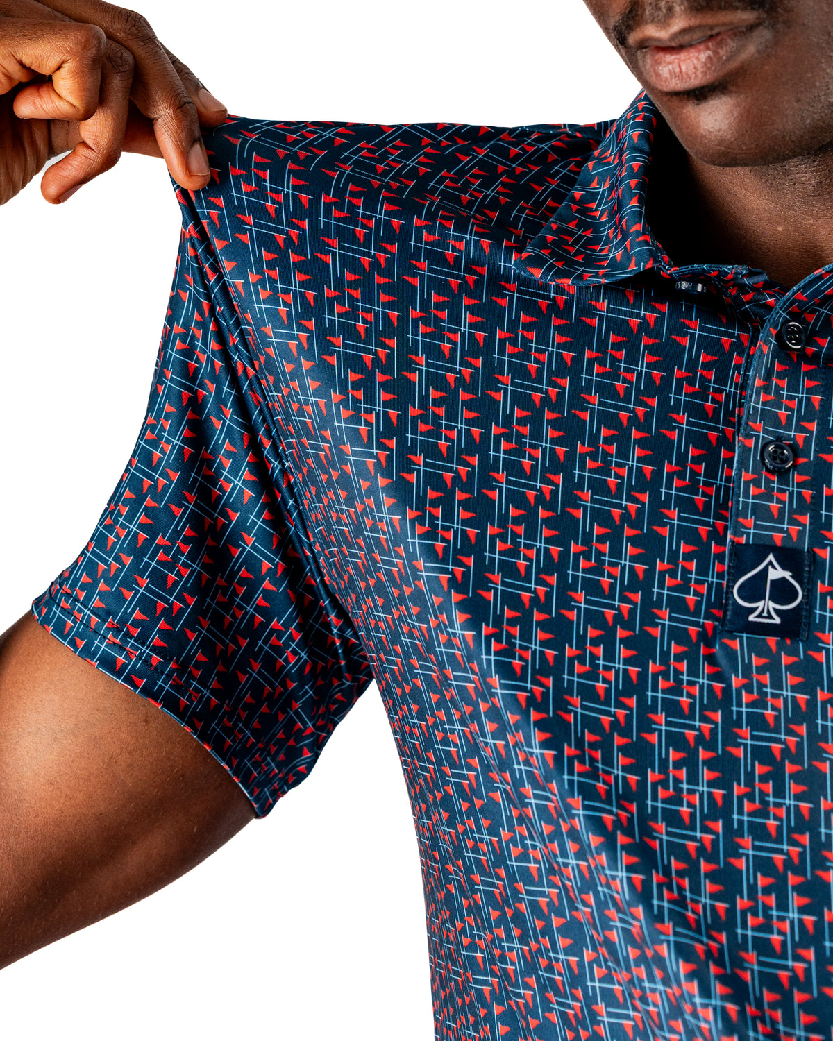 A golfer showcasing a navy polo shirt featuring a bold red and white flag pattern, emphasizing style on the course.