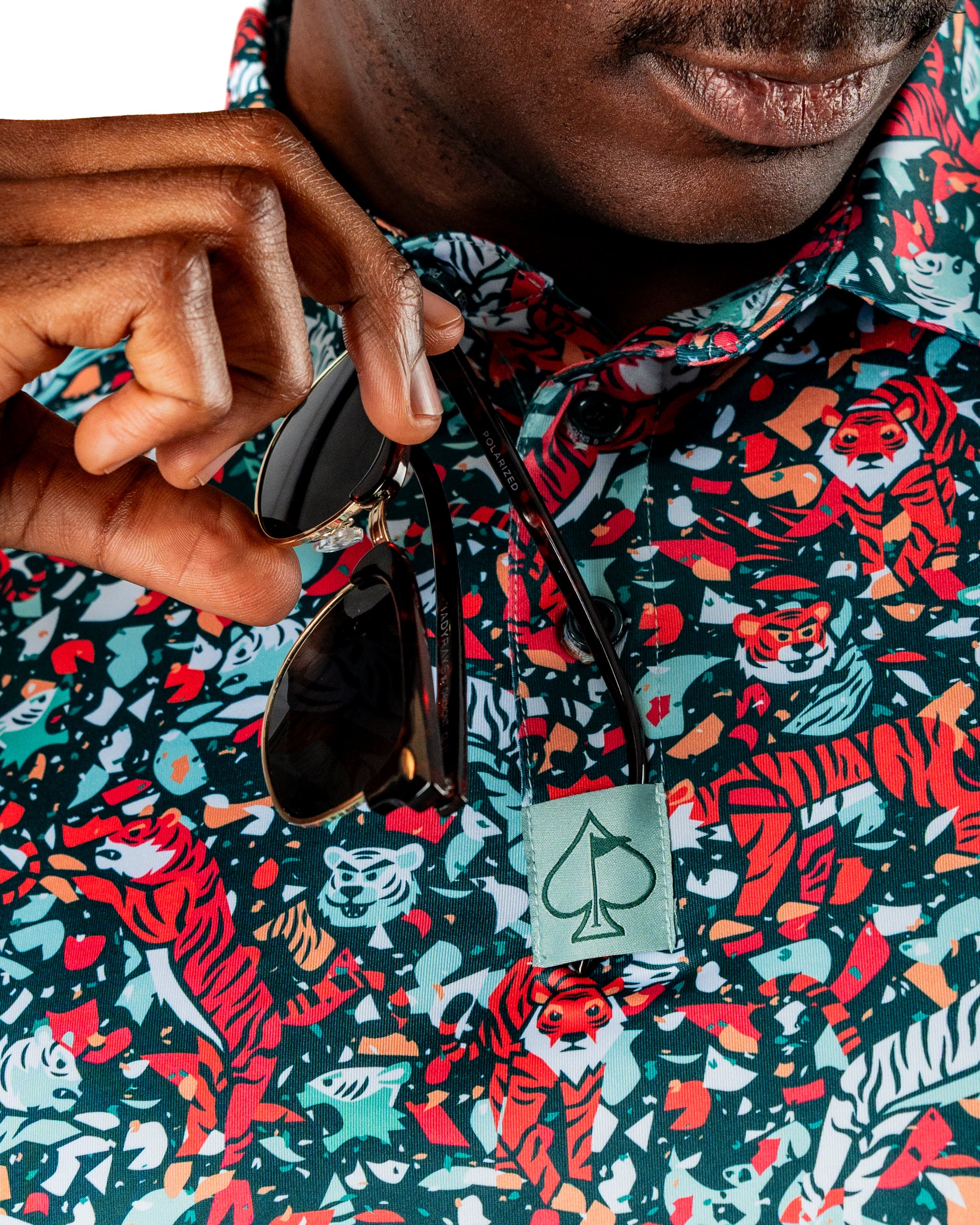 Bold teal golf shirt featuring a vibrant tiger print, with a golfer holding sunglasses and showcasing a stylish collar detail.